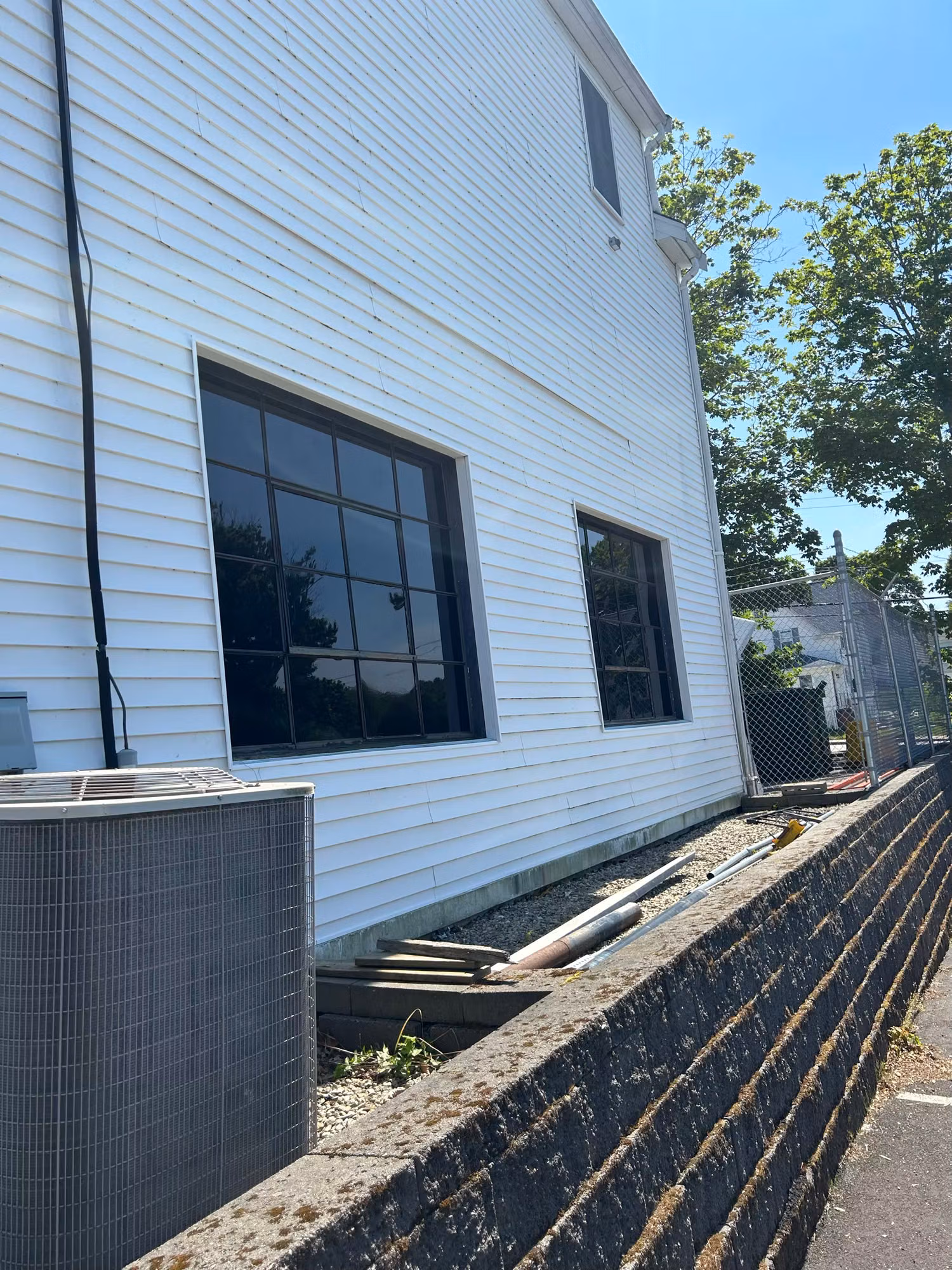 Exterior white clapboard building with grid windows showing dark reflective film for heat and glare control.