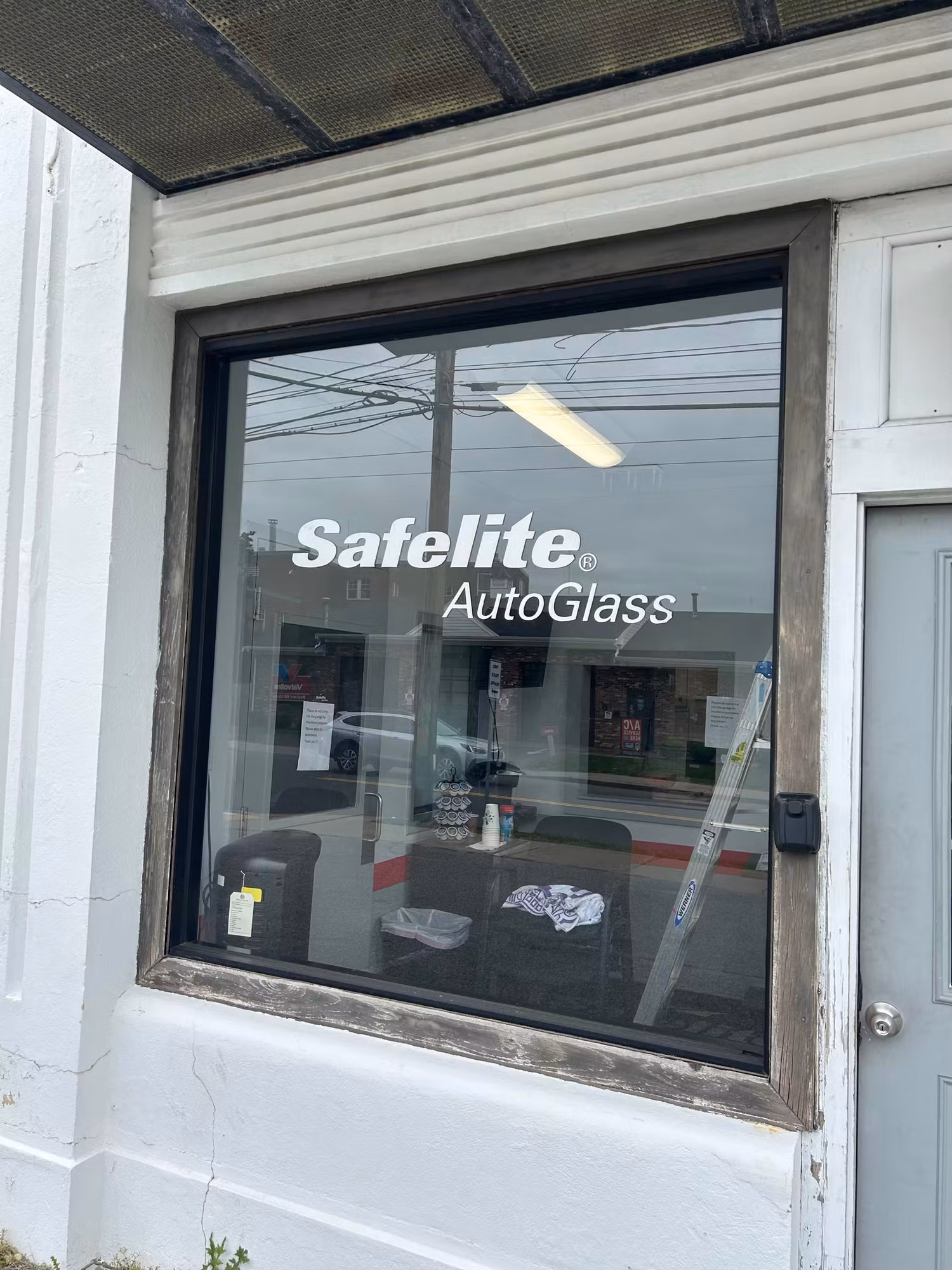 Storefront window with white cut-vinyl lettering applied to the glass facing the street.