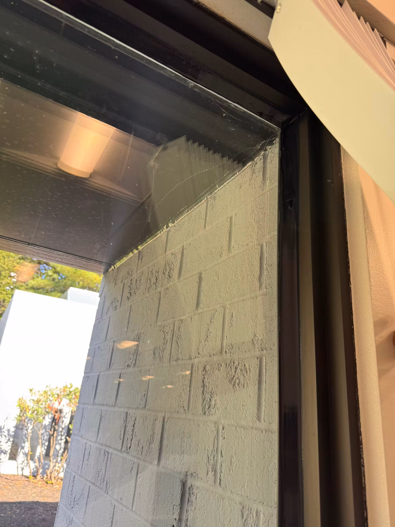 Freshly applied window film with squeegee marks along the edge of a dark commercial office window.