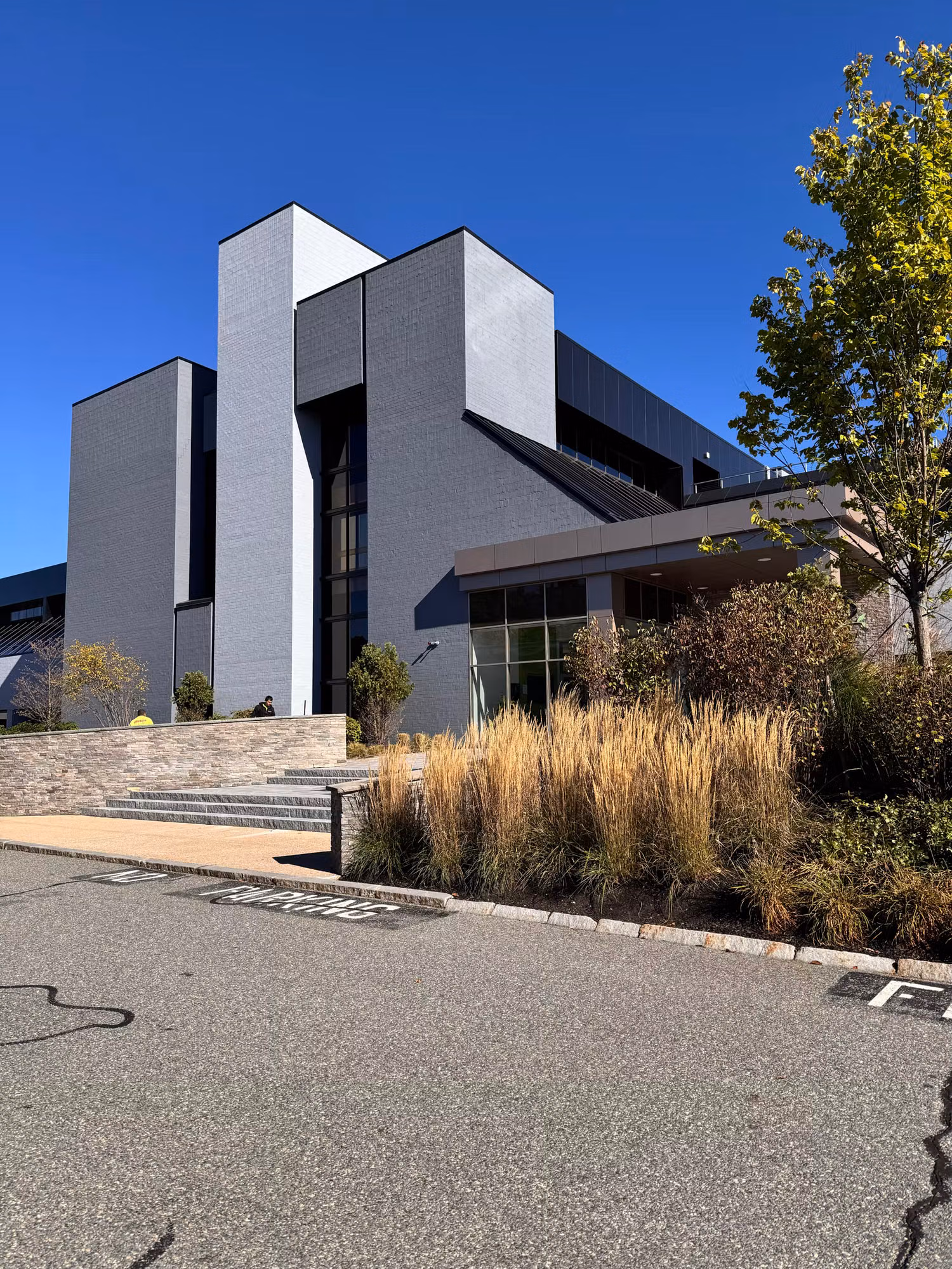 Modern gray office building exterior with large darkened glass windows treated with solar control film.