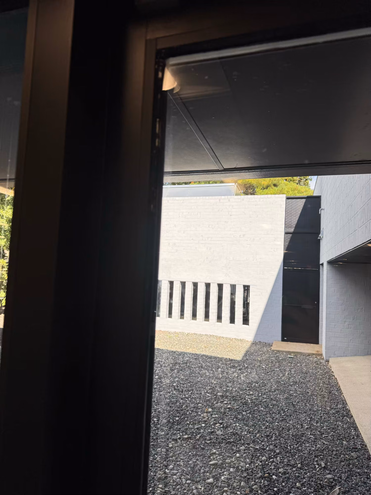 View through a large office window with solar control film out onto a gravel courtyard and white wall.