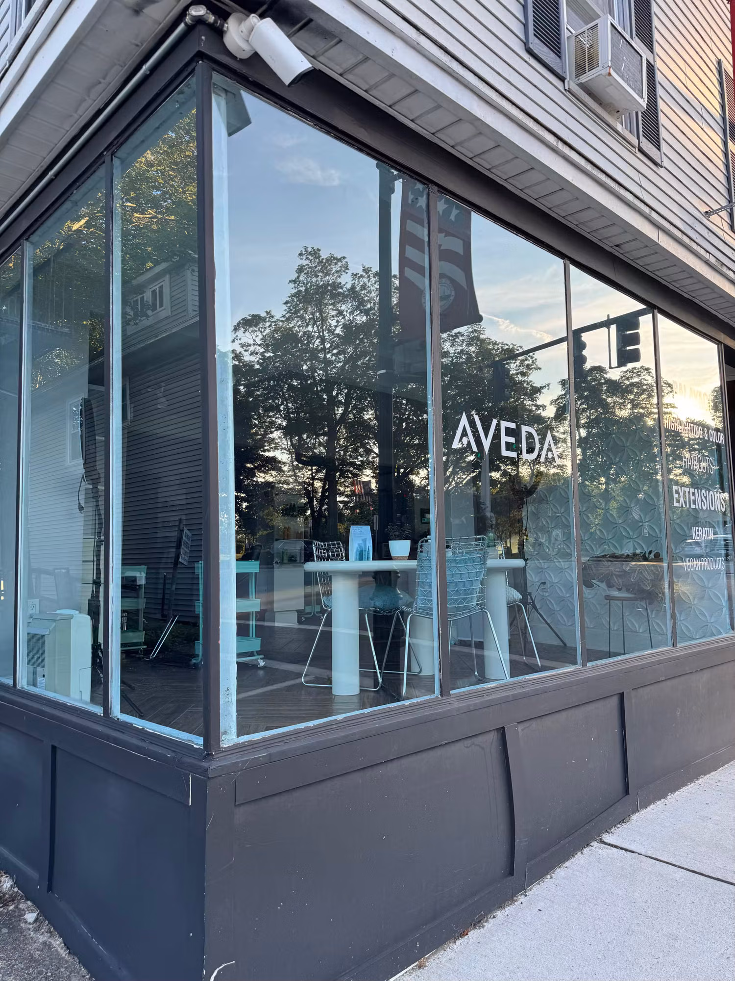 Large wraparound corner storefront windows on a salon with reflective tinted commercial glass facing the street.