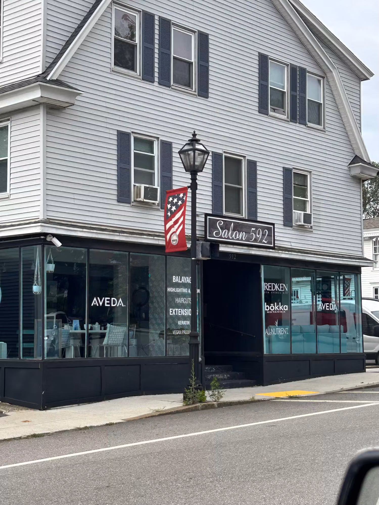 Corner salon storefront with large display windows carrying cut vinyl service lettering and decals on the glass.