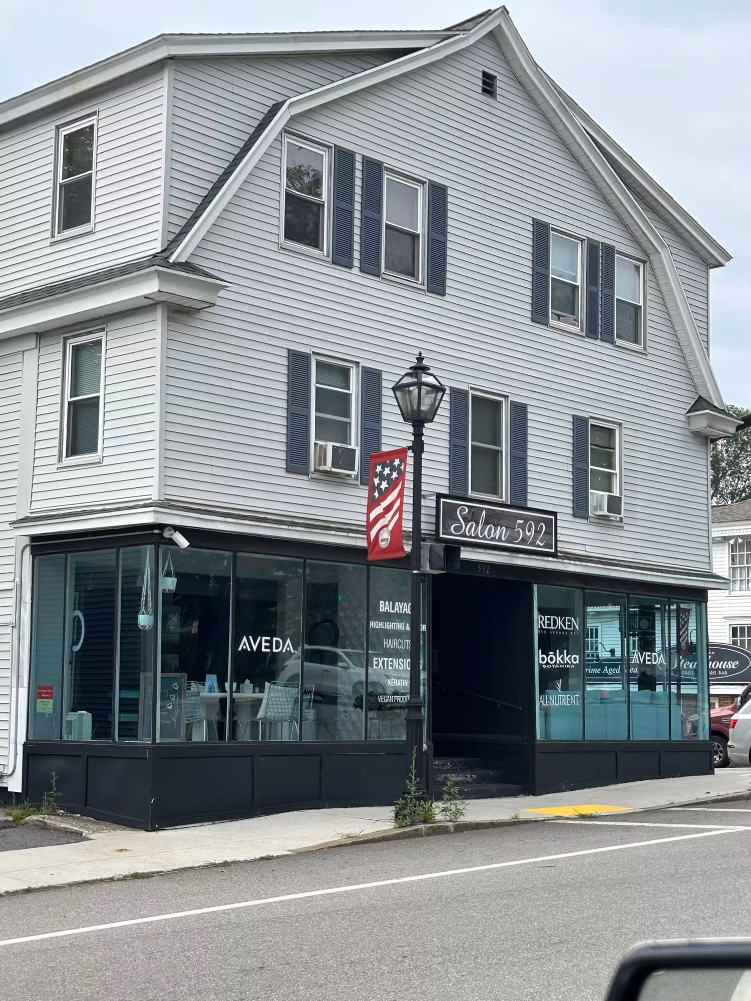 Salon building corner with display windows featuring applied vinyl service text and logo decals along the storefront glass.