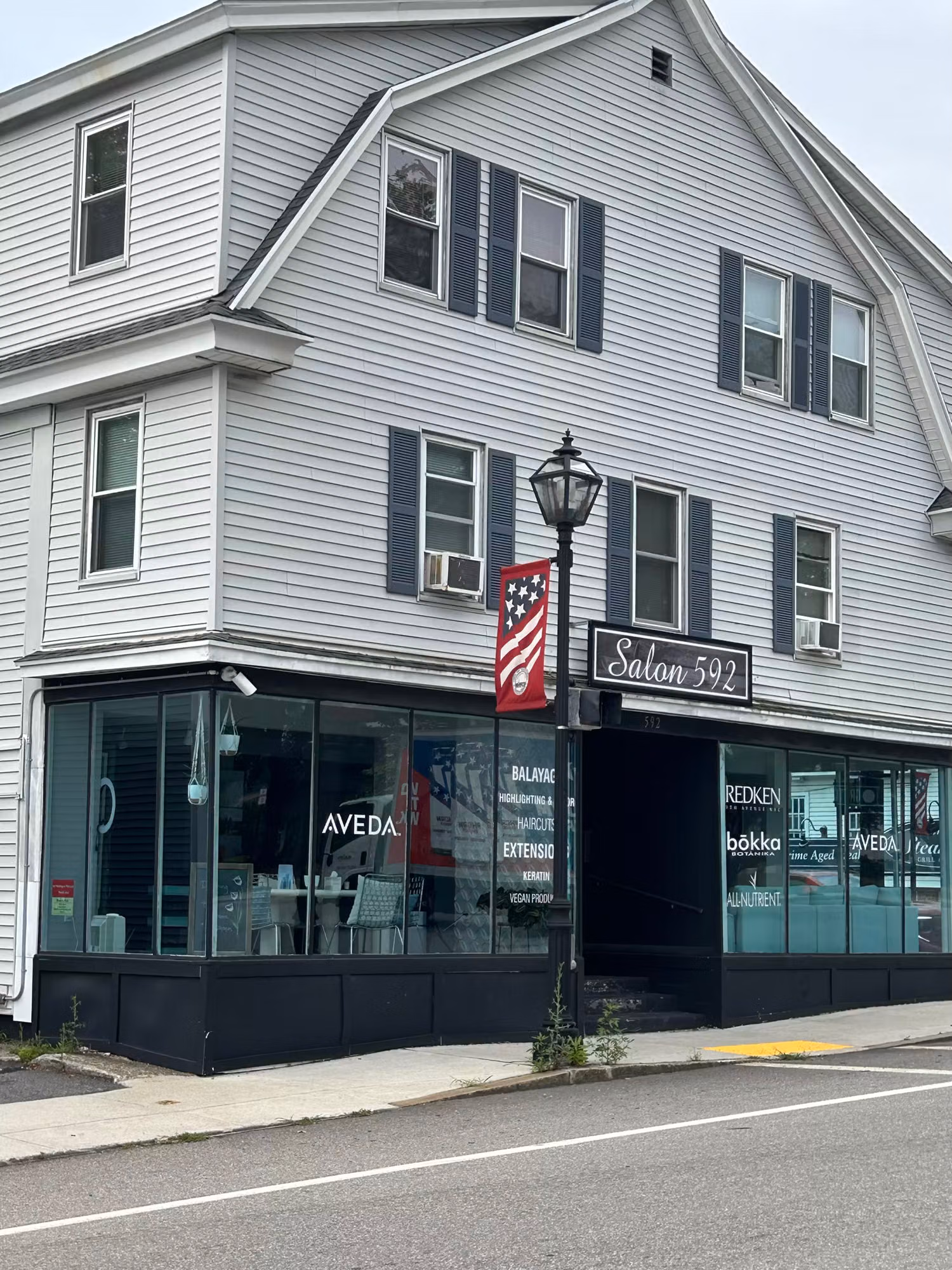 Corner salon storefront showing large windows with cut vinyl lettering and brand graphics applied to the glass.