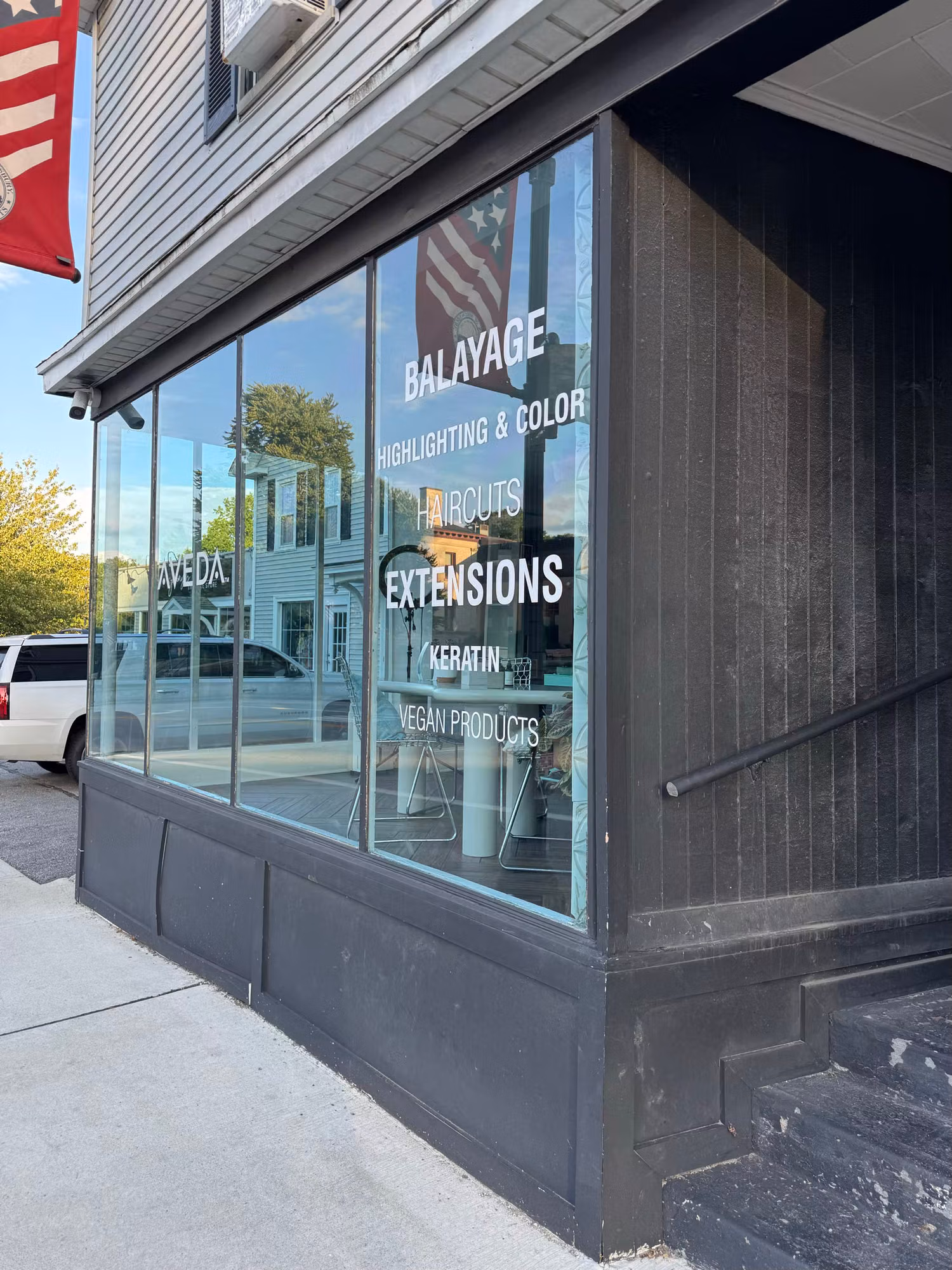 Close view of a salon display window with cut vinyl lettering listing services and brand graphics on the glass.