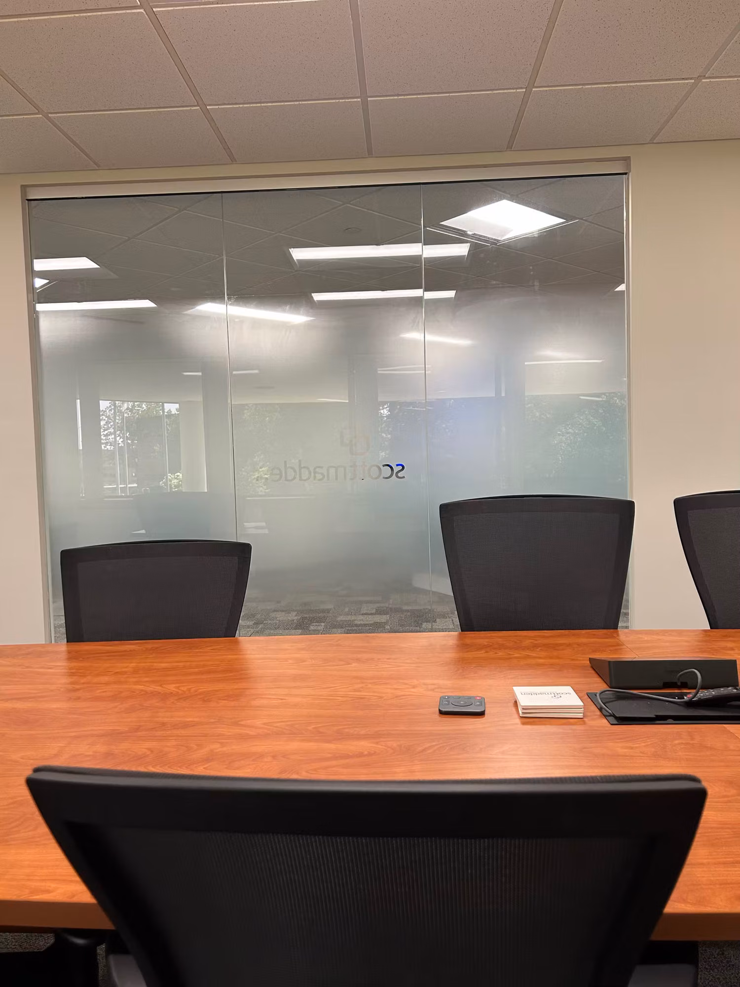 View from inside a conference room toward a glass wall carrying a frosted privacy film band for meeting privacy.