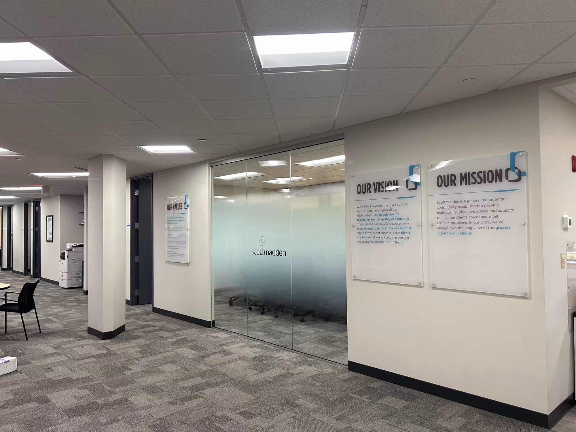 Open office area with a glass conference room partition wrapped in a frosted privacy film band for added seclusion.
