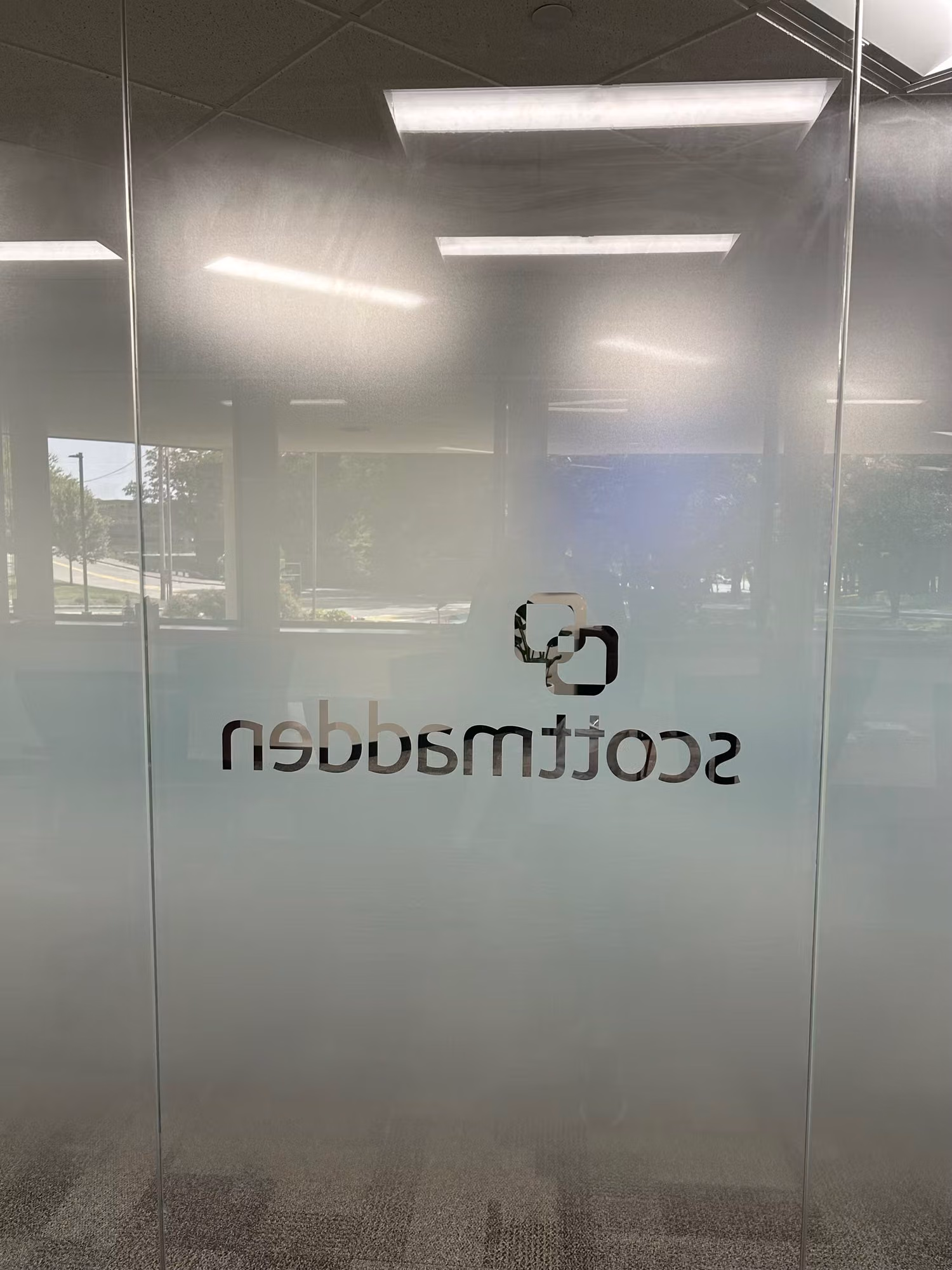 Frosted privacy film with a gradient band applied to a floor-to-ceiling glass office partition wall.