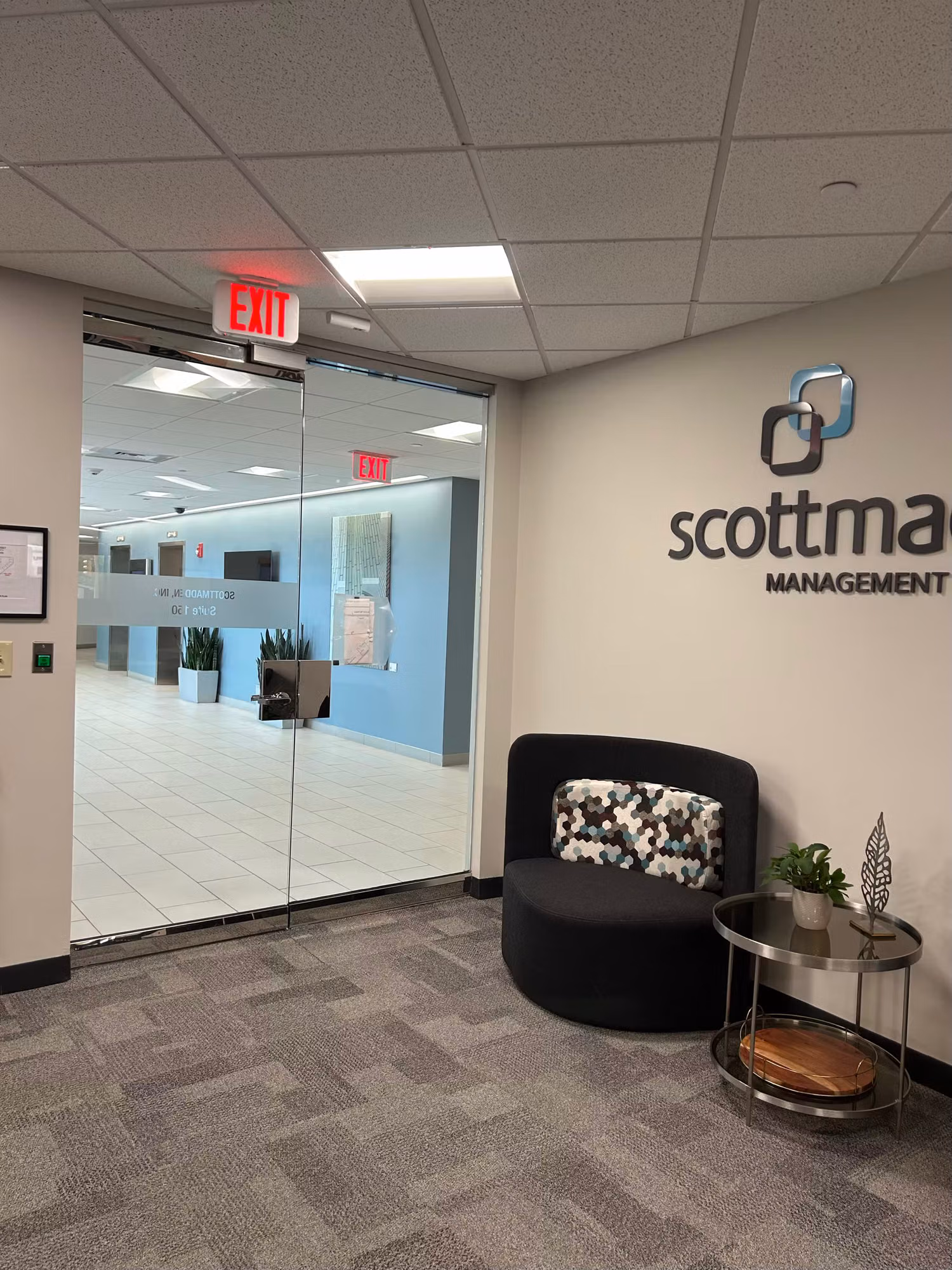 Reception lobby with a floor-to-ceiling glass entry wall and doors leading into a tiled corporate office space.