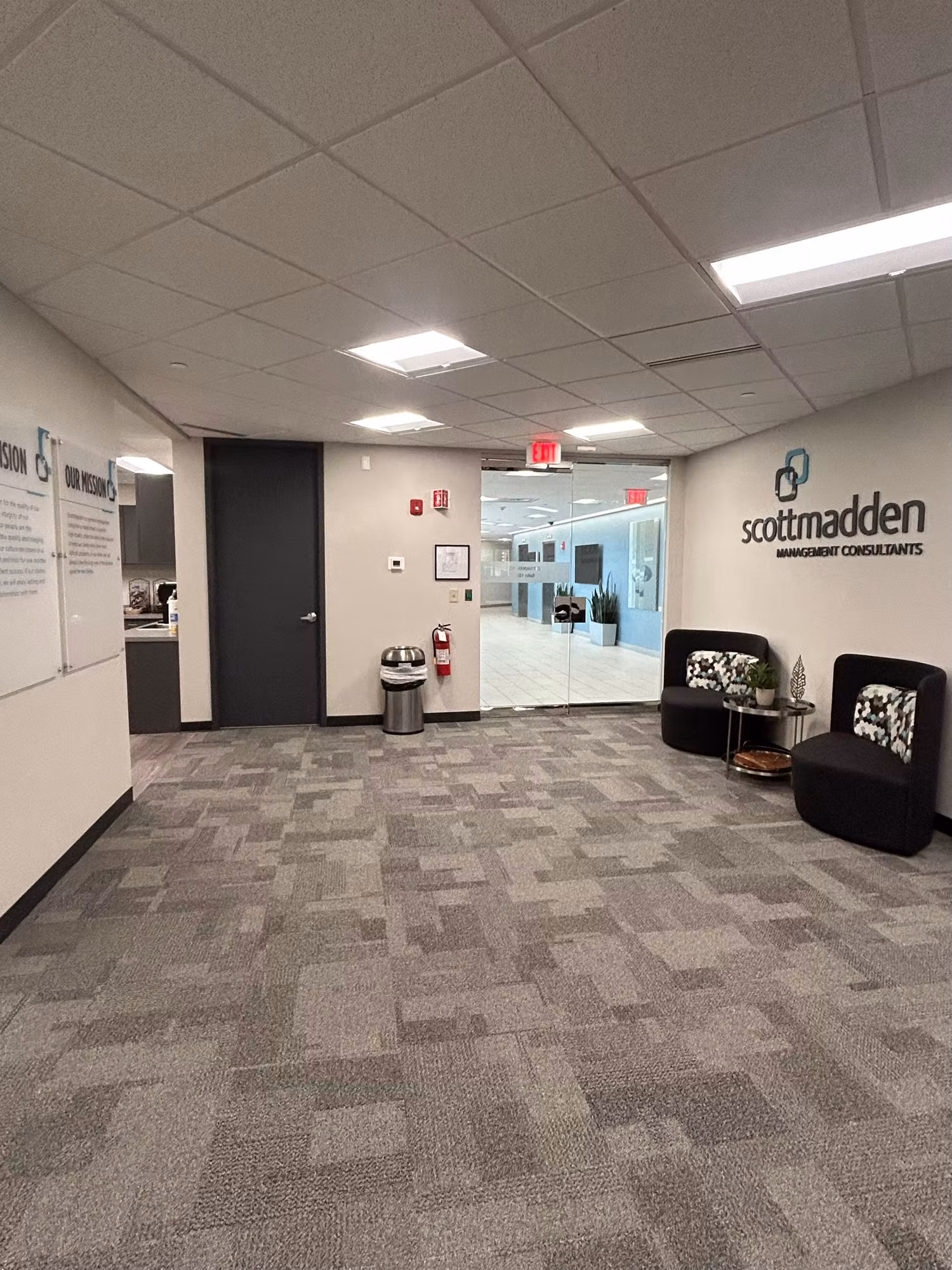 Open office lobby with a floor-to-ceiling glass entry wall and doors leading into the building interior.