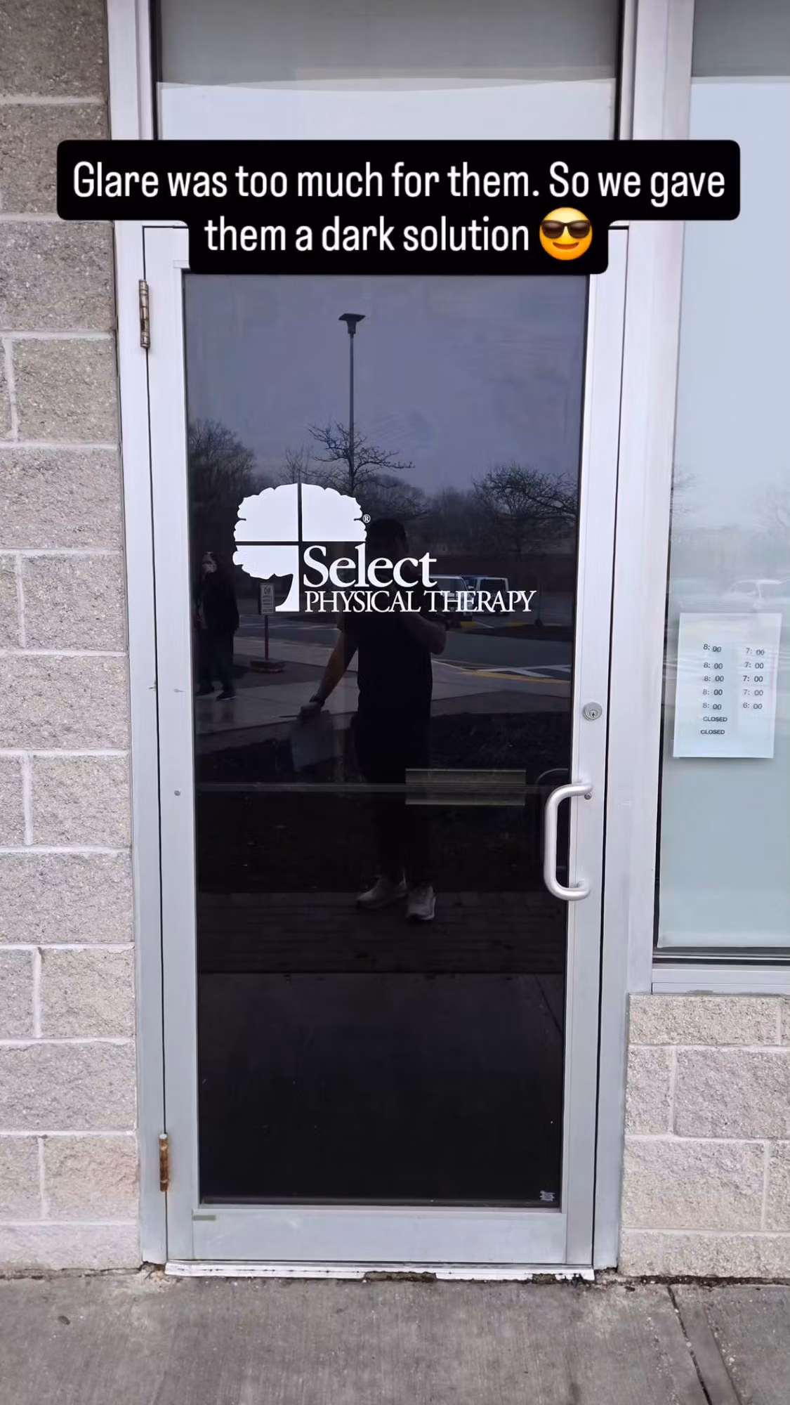 Commercial glass entry door fitted with dark solar control film to cut glare, with logo lettering on the glass.