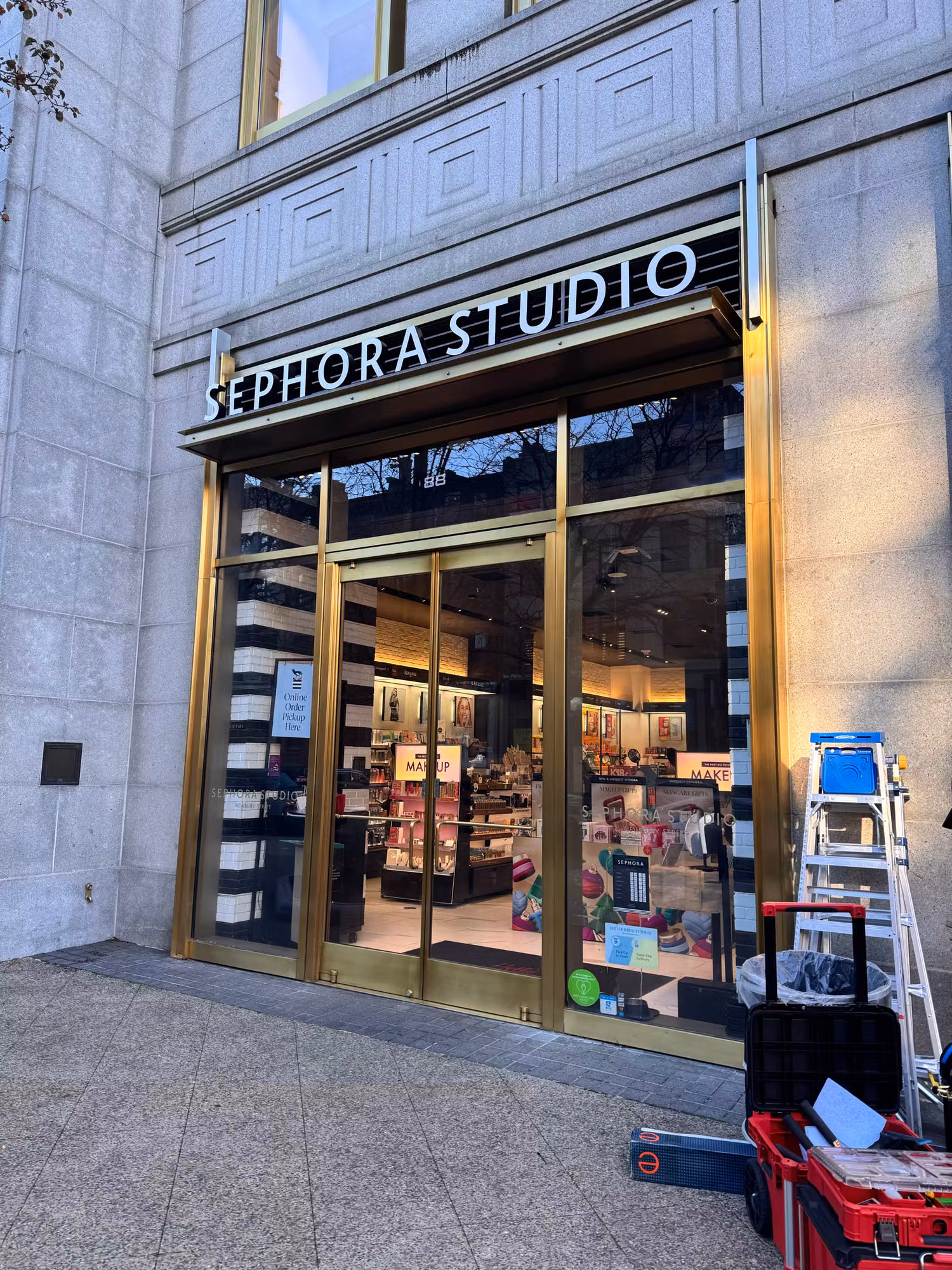 Brass-framed retail storefront with floor-to-ceiling glass windows and entry doors during a window film installation.