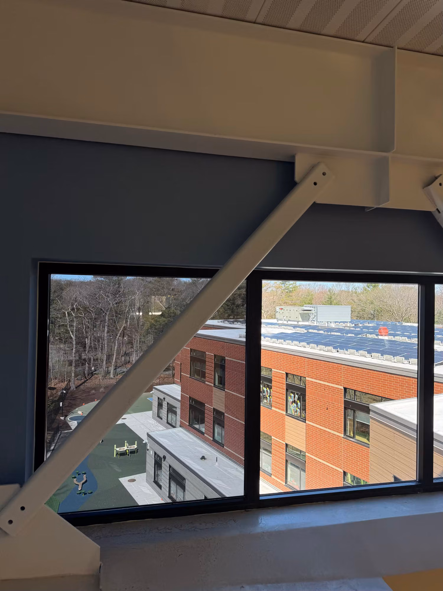 Upper-floor window overlooking a courtyard and a red-brick building across the way.