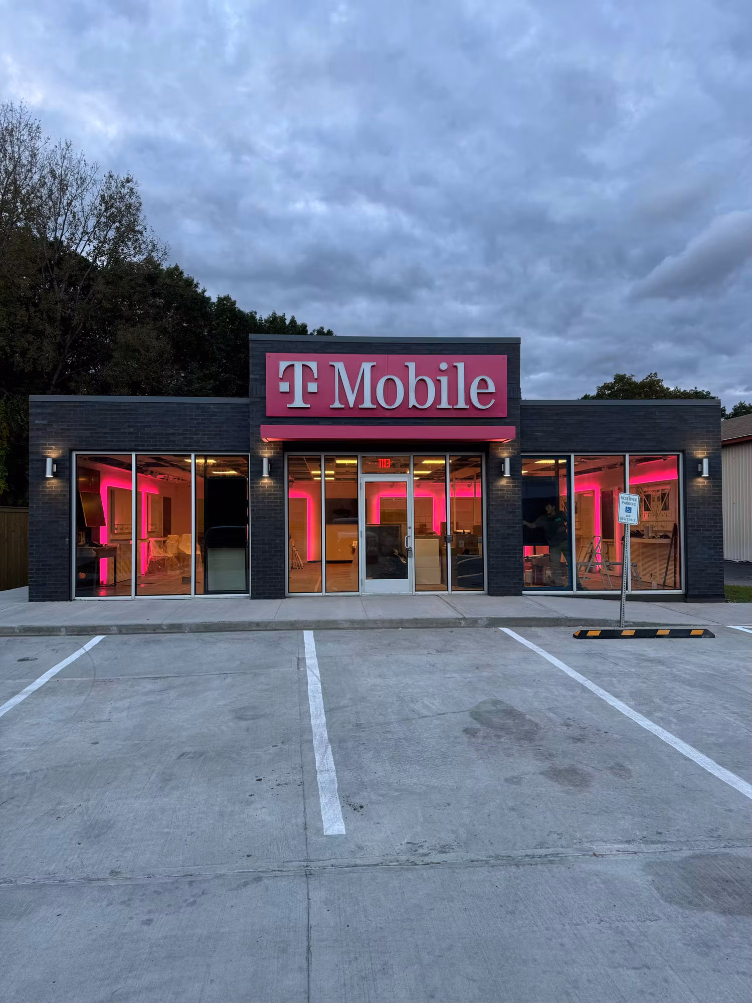 Full exterior of a retail store at dusk with large storefront windows and lit interior glowing through the glass.