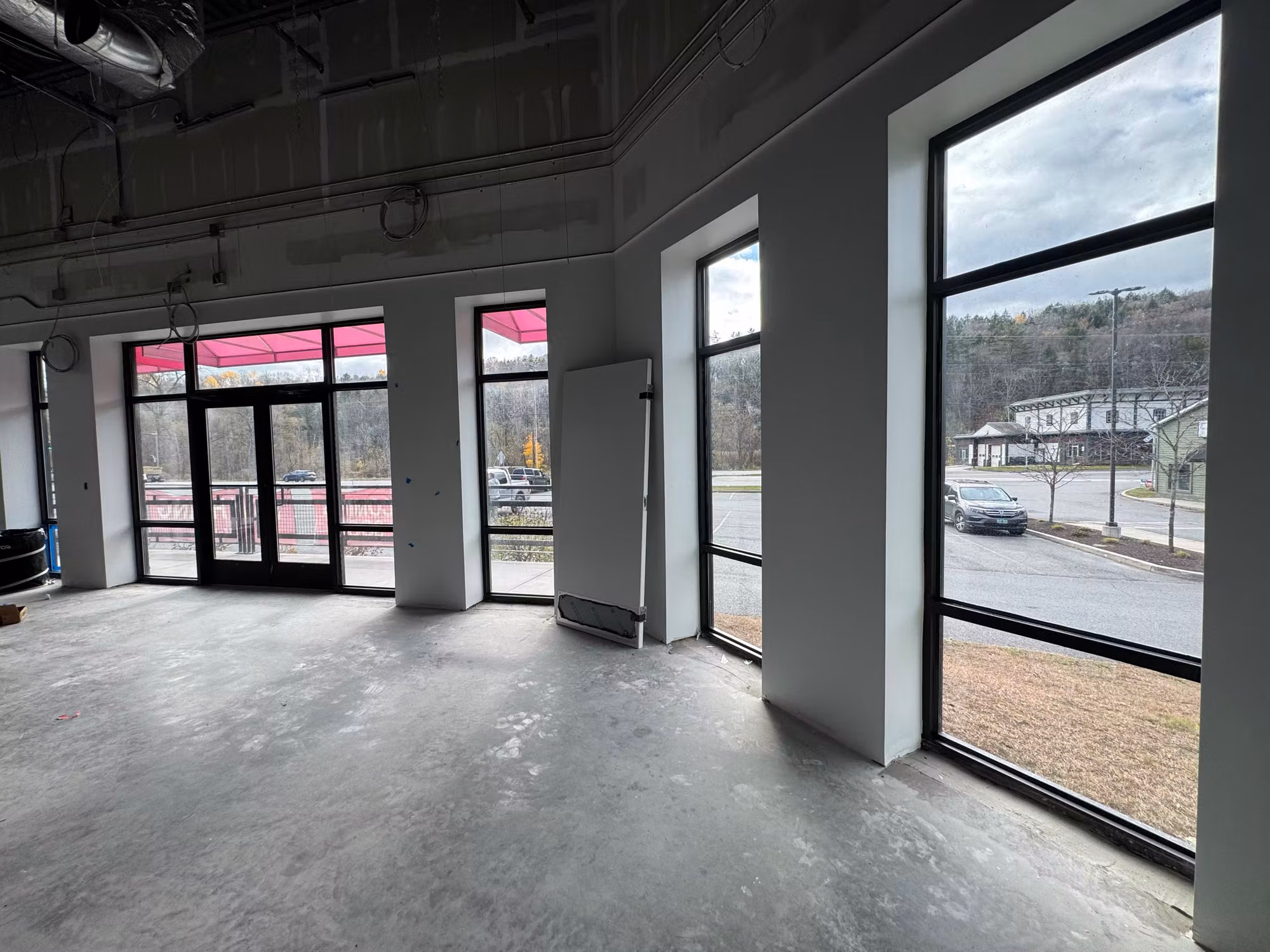 Tinted floor-to-ceiling storefront windows and glass entry doors in a commercial retail space under buildout.