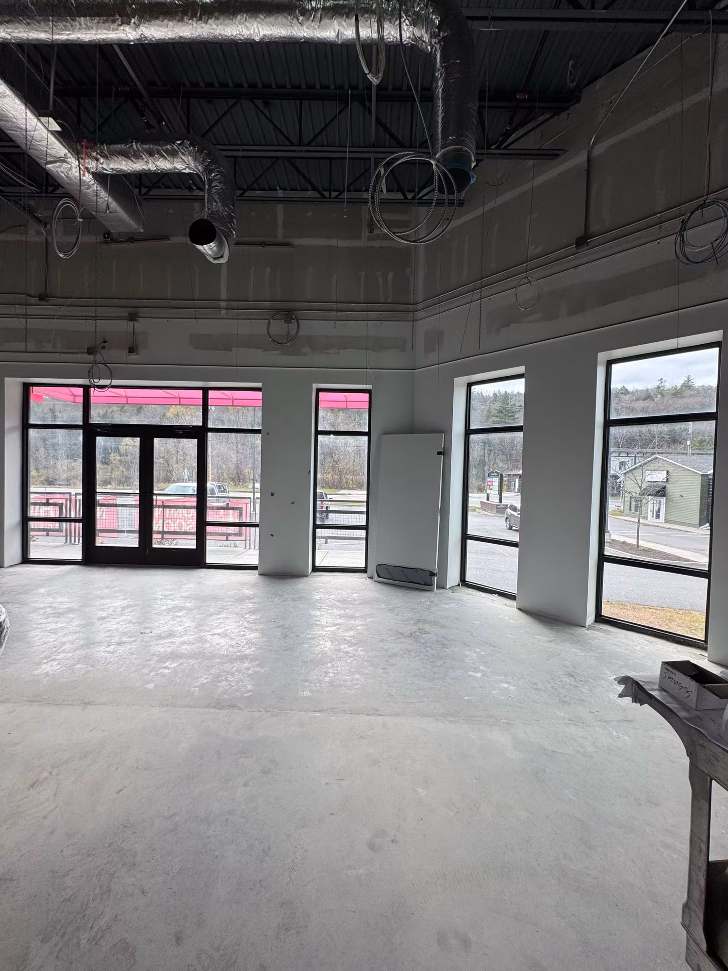 Tinted full-height storefront windows and glass doors in an open commercial interior with exposed ceiling.