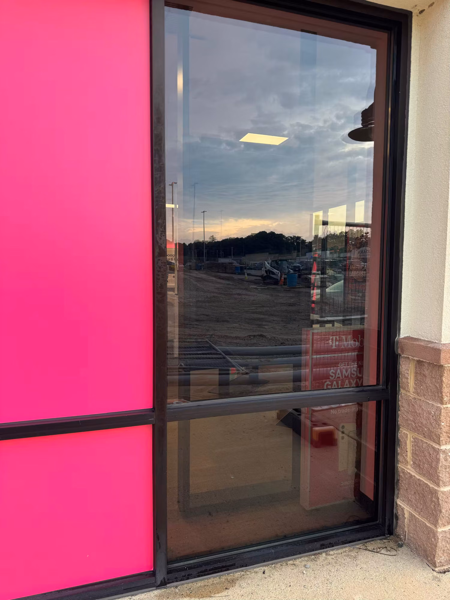 Glass storefront entry door beside a bright magenta decorative window film panel on the retail facade.