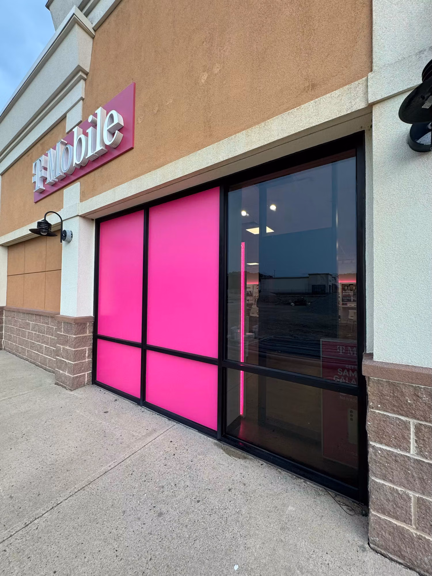 Storefront entry with solid magenta decorative window film panels next to a clear glass door.
