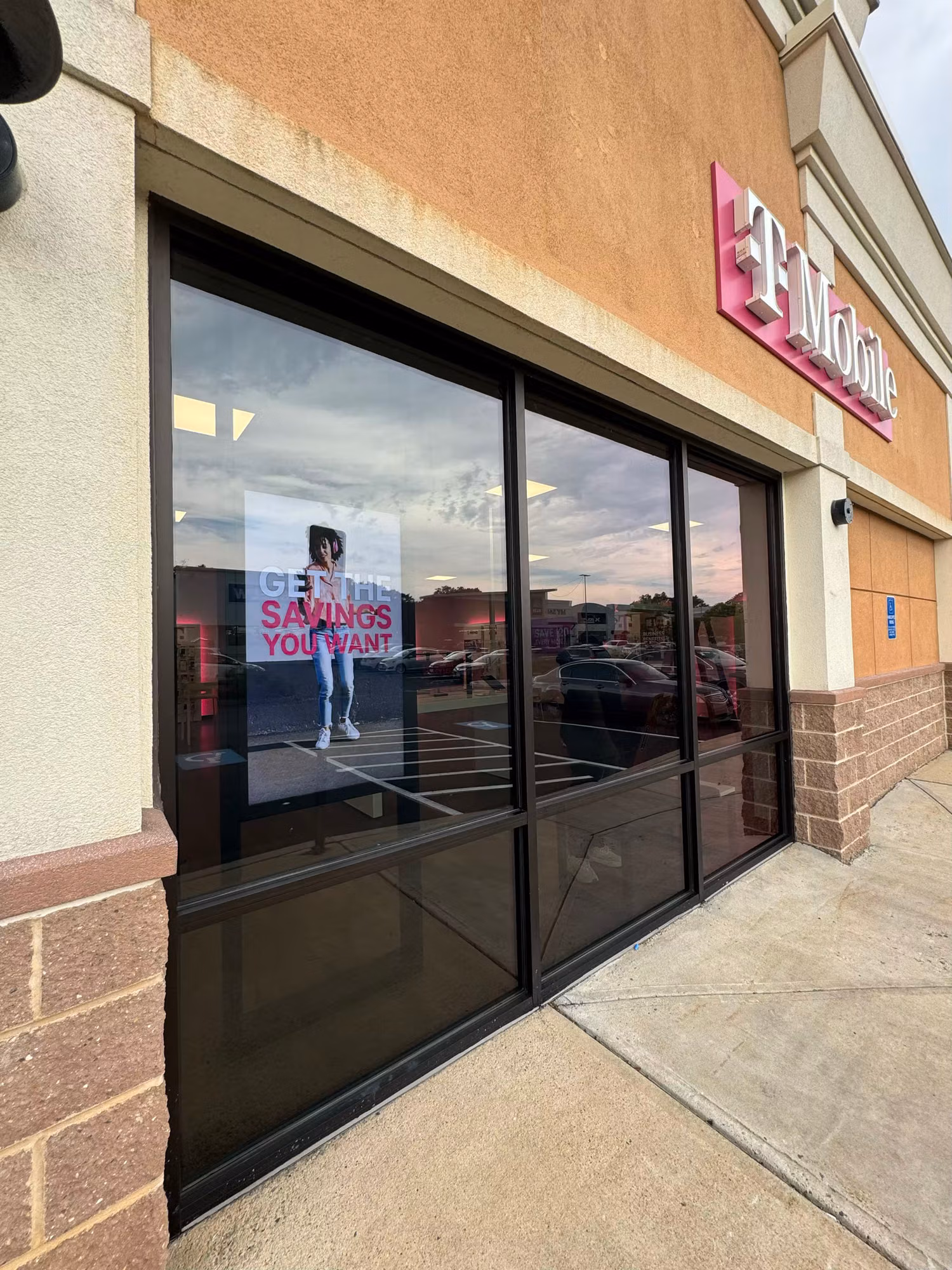 Large solar-control tinted display window at a retail storefront with a promotional poster inside.