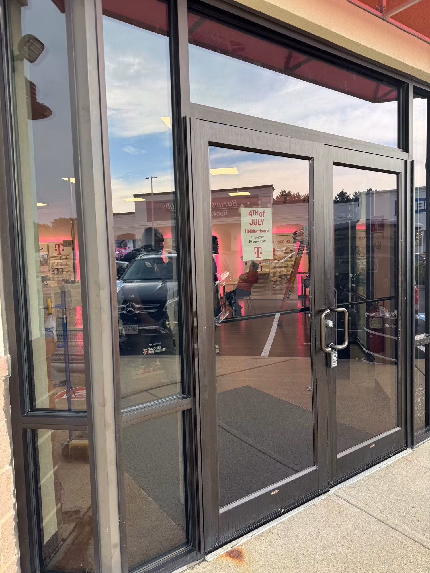 Retail storefront double glass entry doors with solar-control tint flanked by tinted sidelight windows.