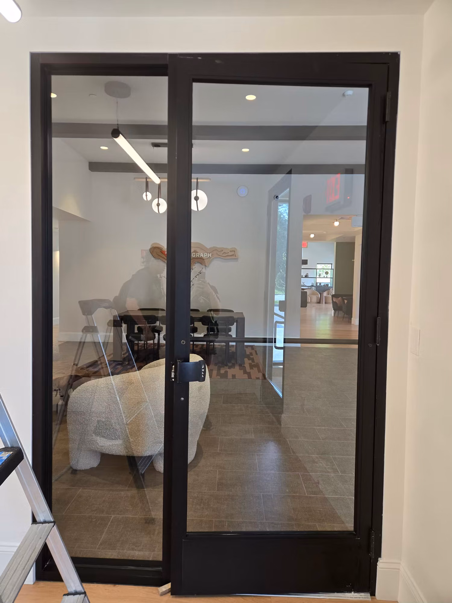 Black-framed interior glass partition doors with a thin tint band across clear glass into a bright room.