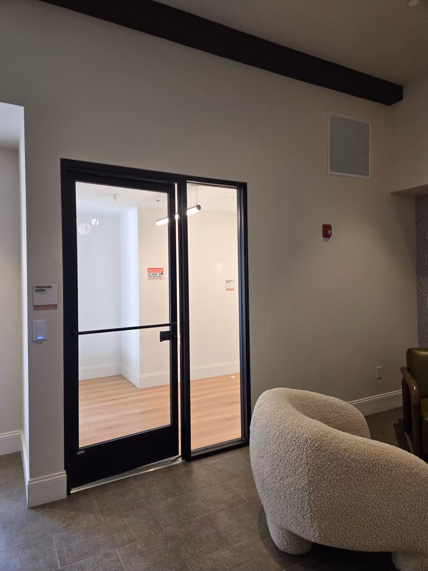 Black-framed interior glass partition doors with a thin tint band, beside a lounge seating area.