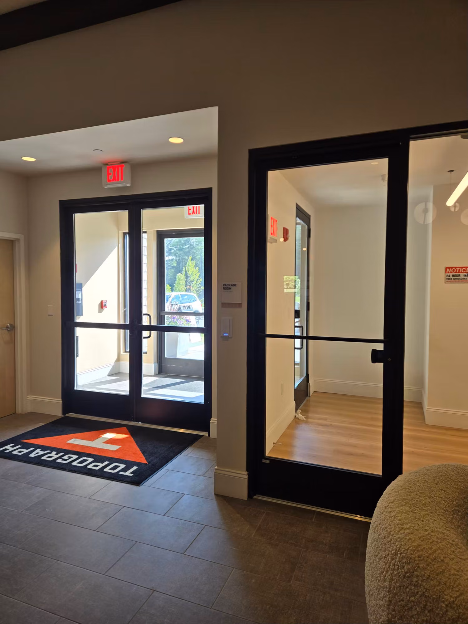Lobby with black-framed glass entry doors and an interior glass partition door carrying a thin tint band.