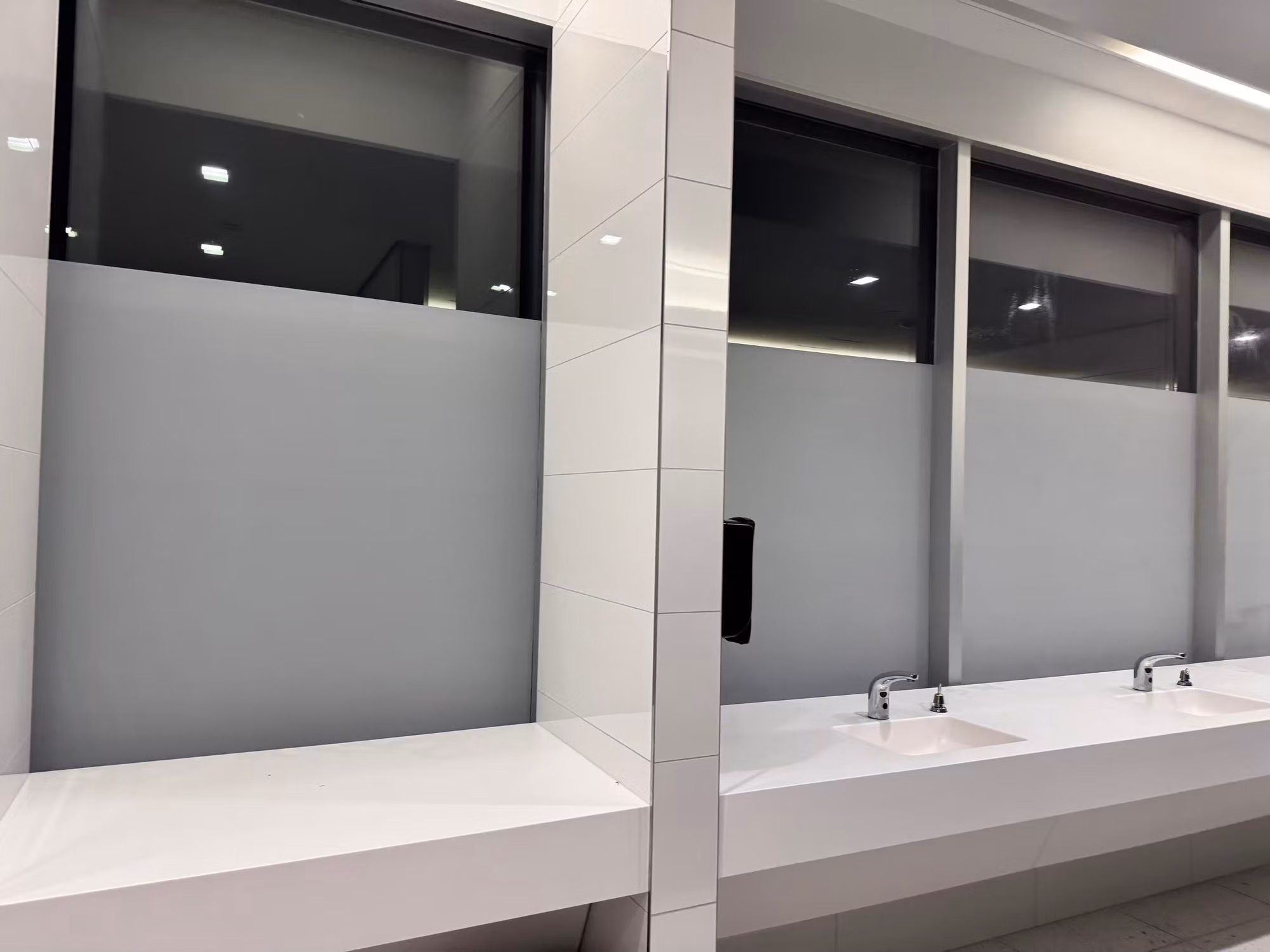 Frosted privacy band applied to the lower windows above a commercial restroom sink counter, clear glass above.
