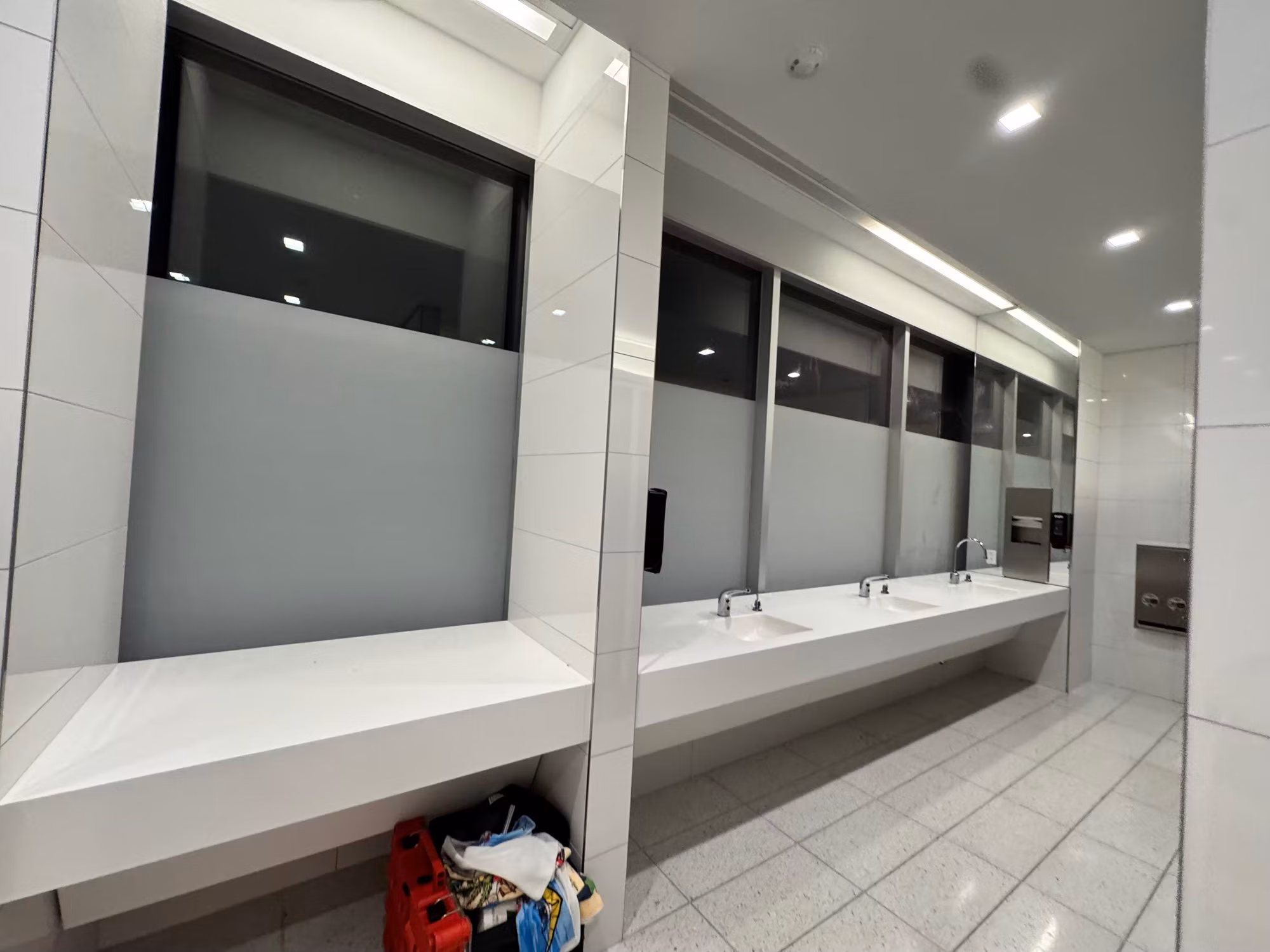 Frosted privacy film on lower restroom windows above a long sink vanity, with clear glass panels above.