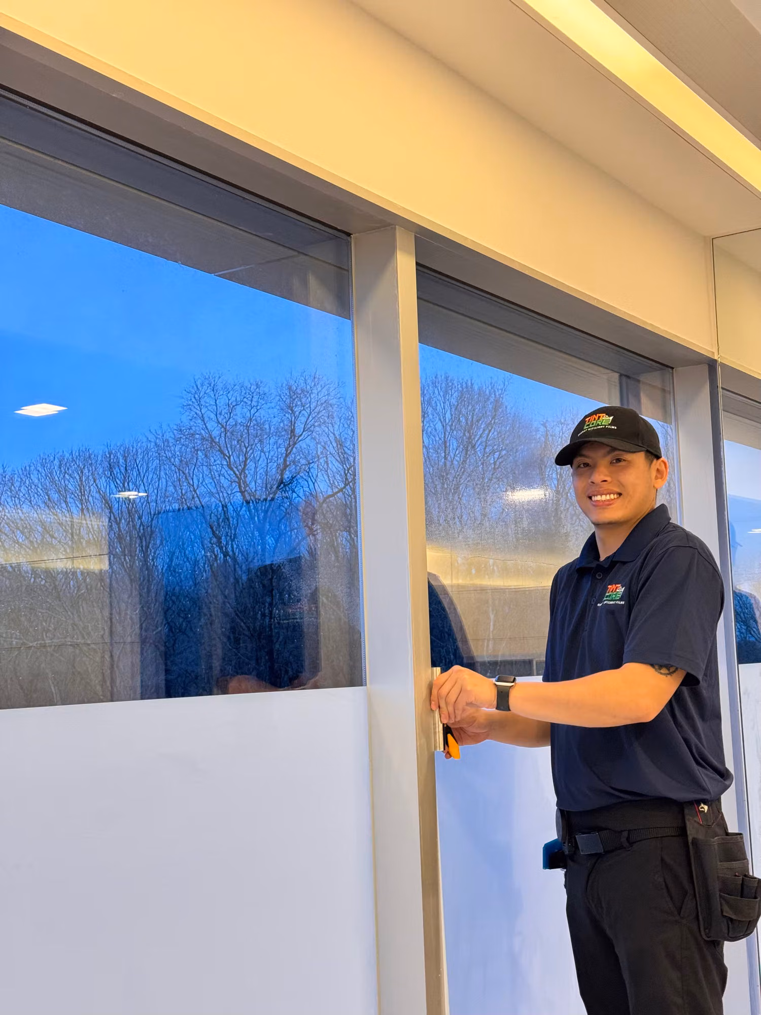 Installer applying window film to a large commercial storefront entry window using a hand squeegee.
