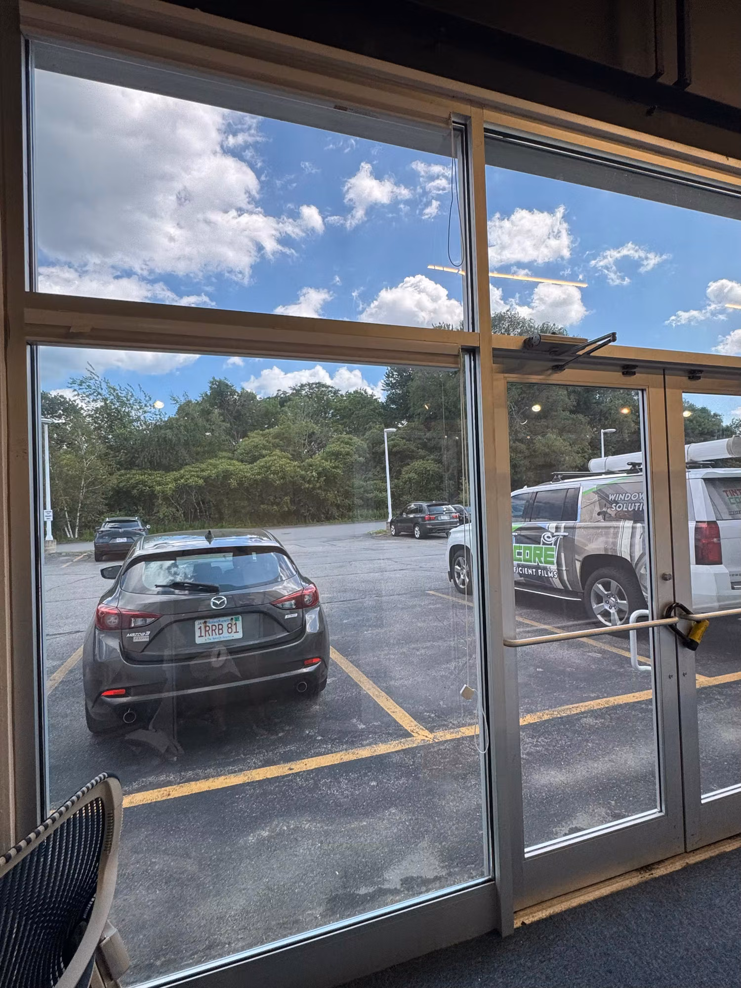 Tinted storefront window wall and glass door seen from inside, reducing glare from the bright parking lot.