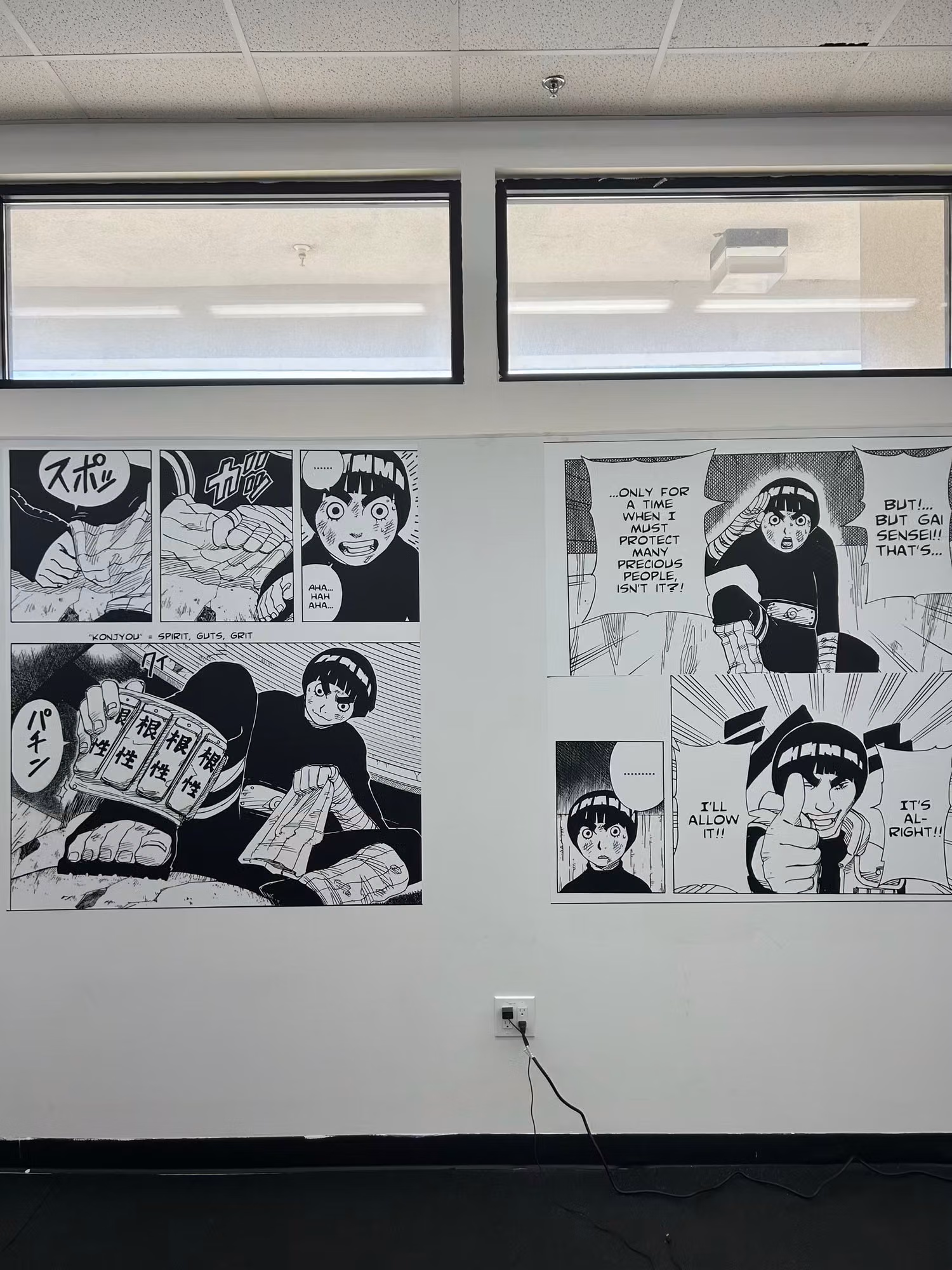 Black-and-white manga-style wall wrap graphics applied to an interior gym wall below clerestory windows.