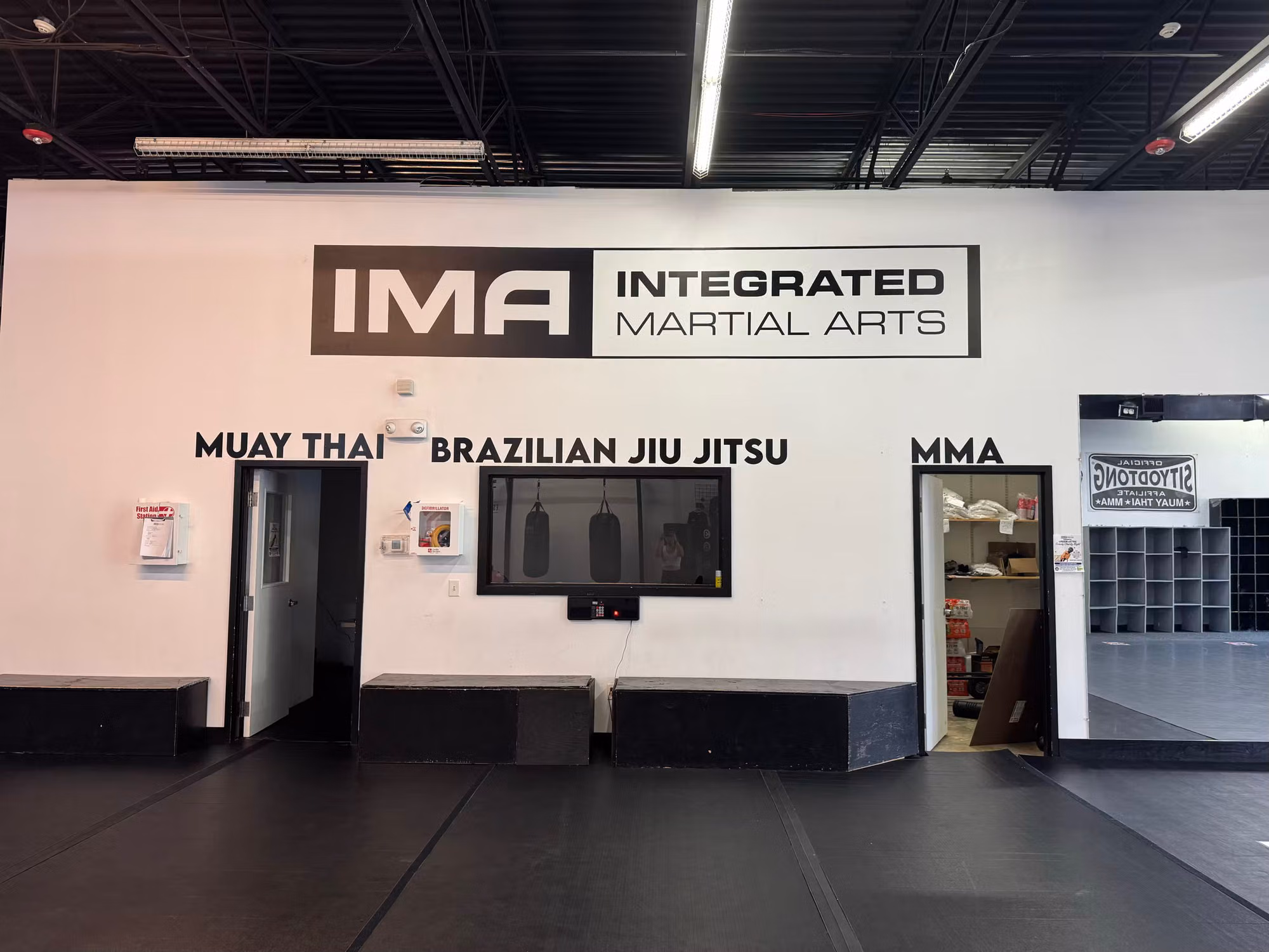 Interior gym wall with applied vinyl logo and cut lettering above the training floor and equipment.