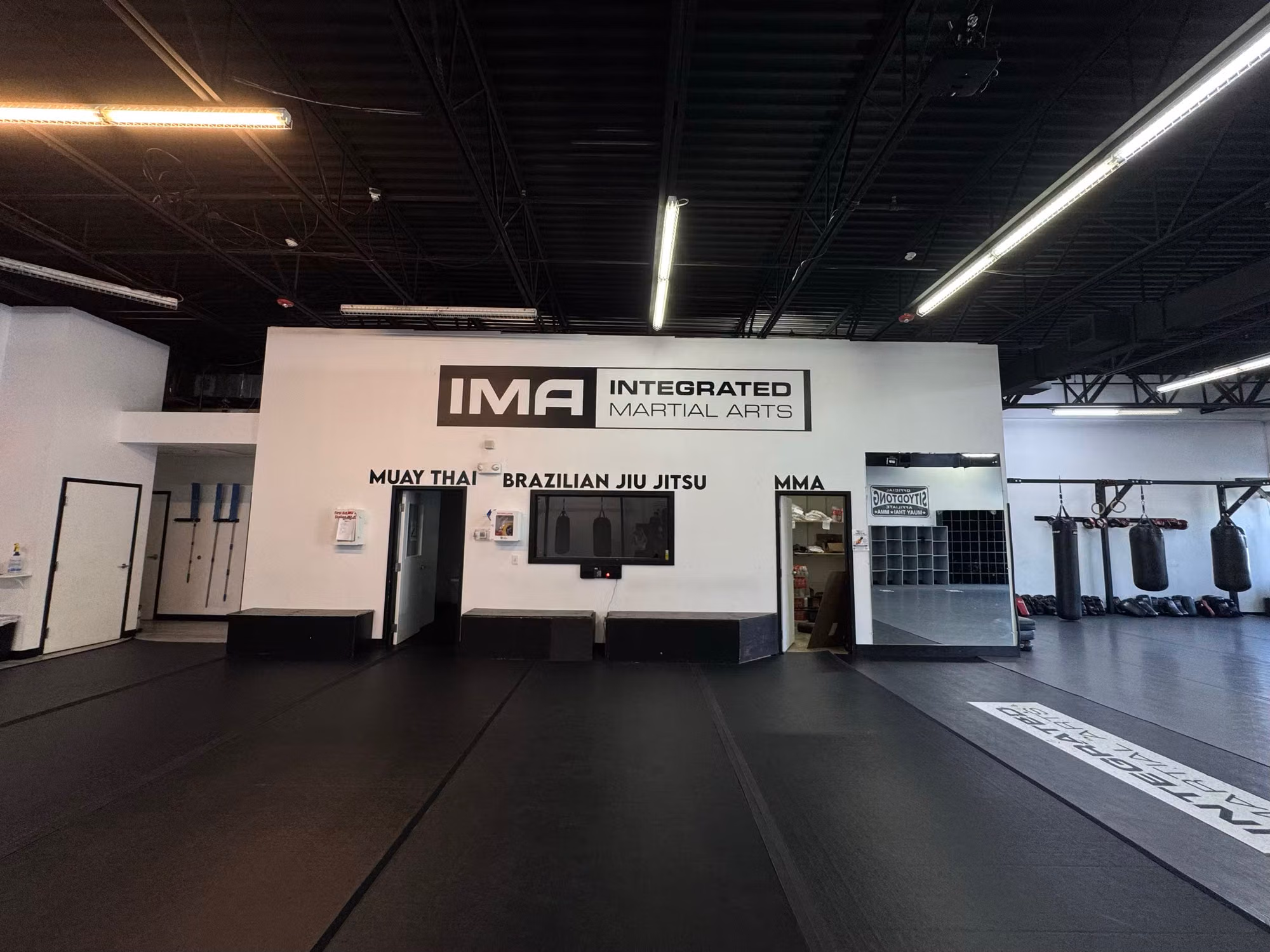 Wide view of a gym training floor showing applied vinyl wall logo and cut lettering on the back wall.