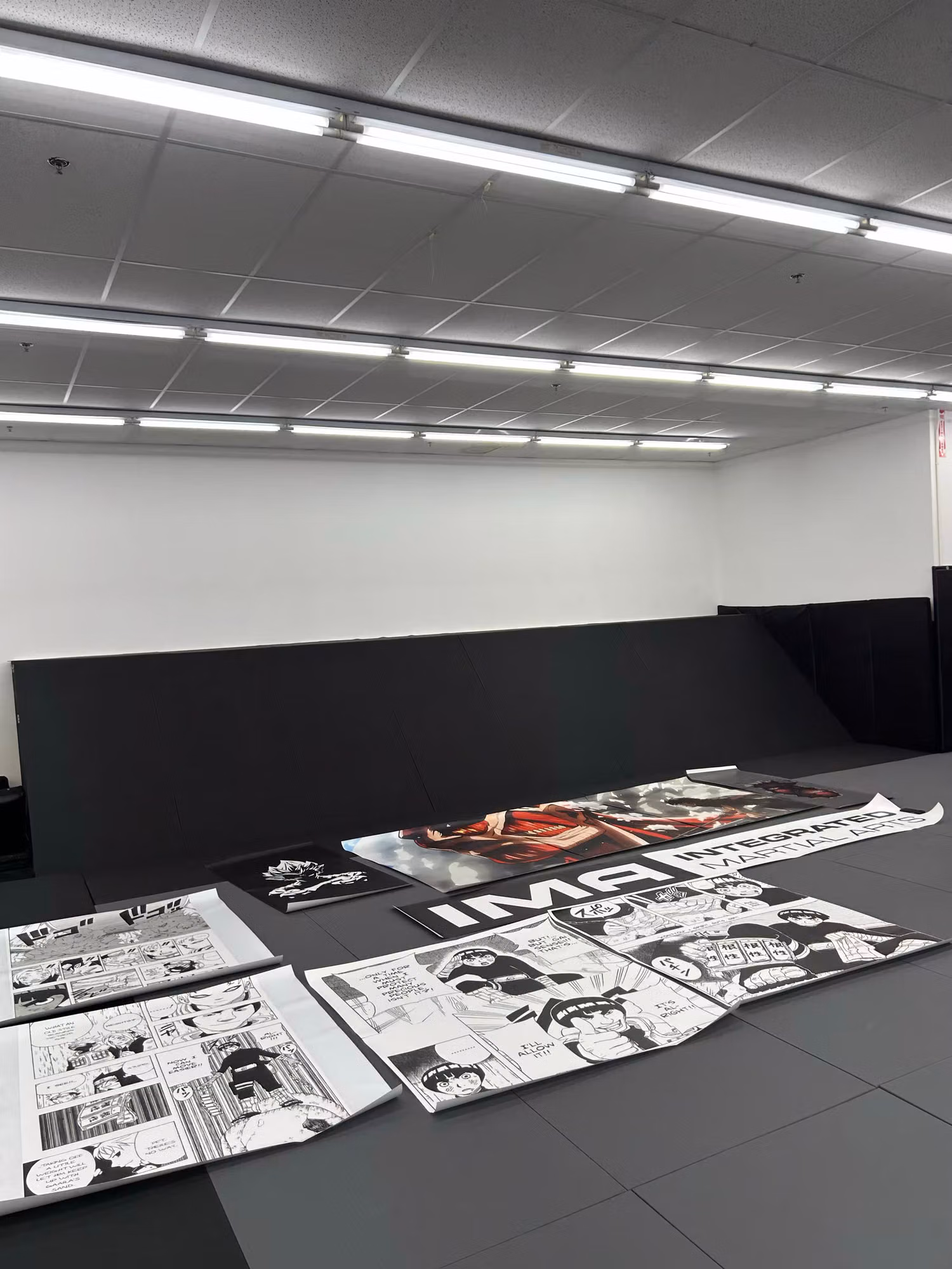 Black and white printed wall-graphic panels staged across a gym floor ready to be applied to the walls.