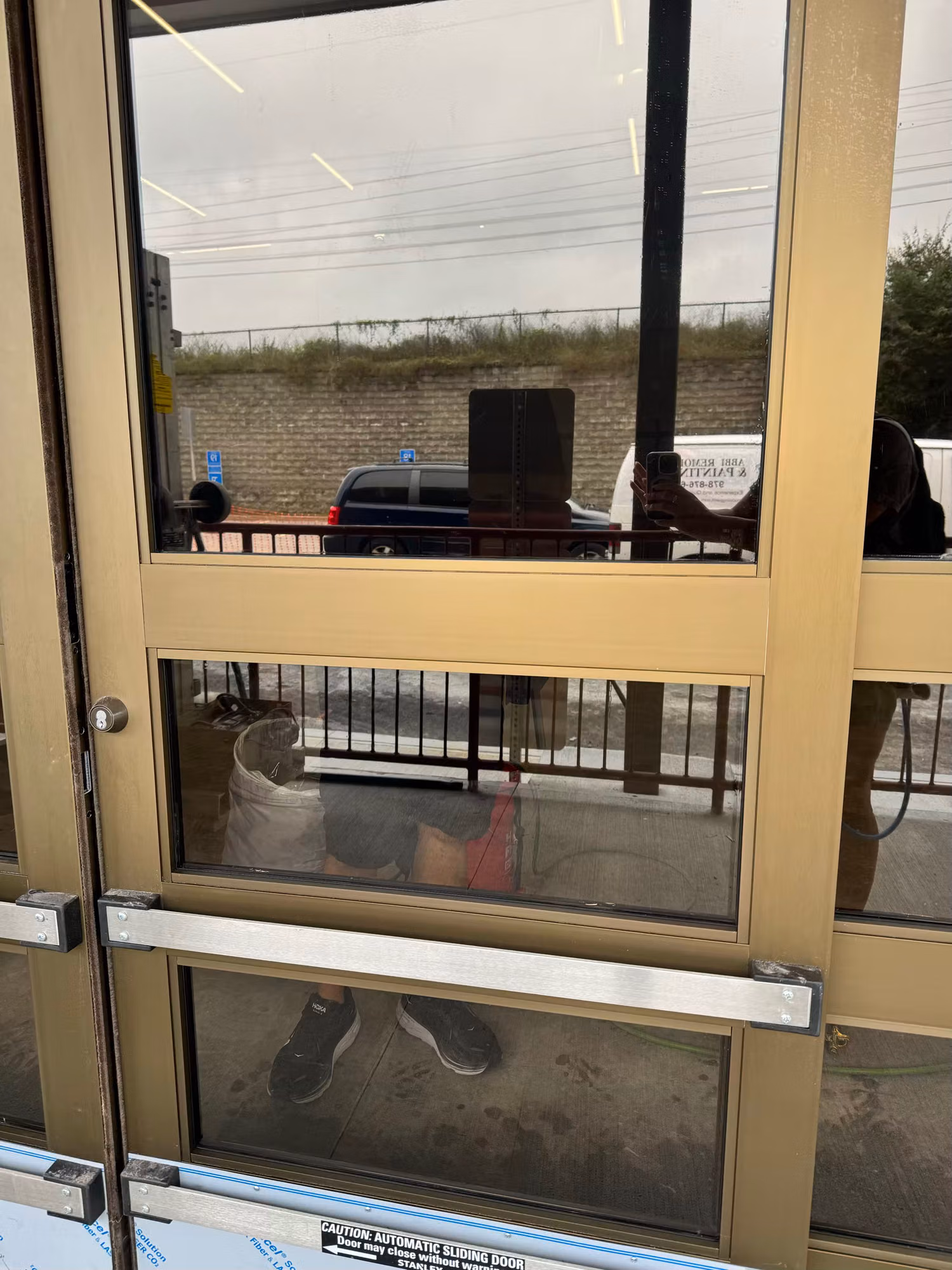 Close view of tinted glass on commercial automatic sliding entry doors with a reflective film over the panels.