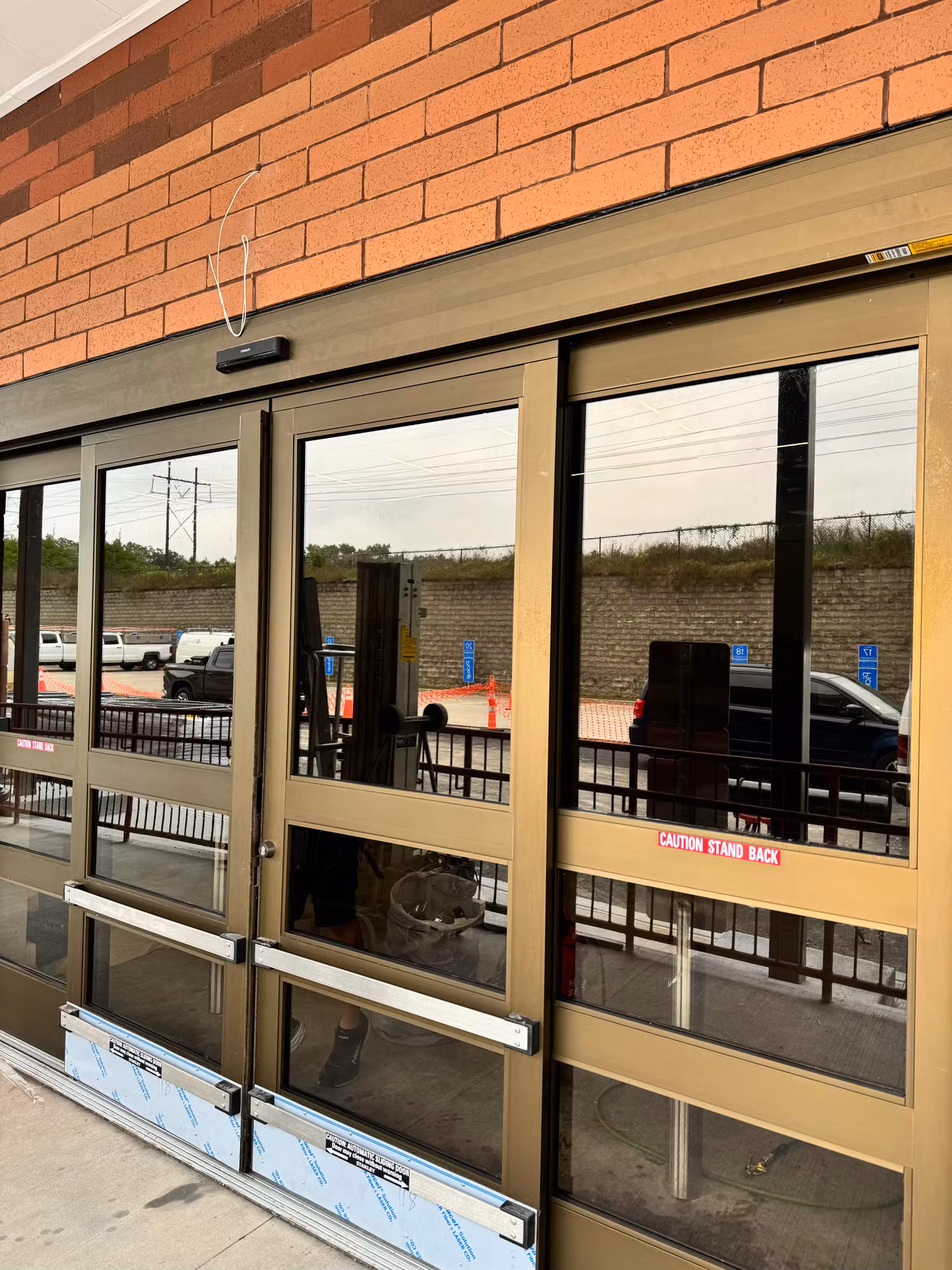 Commercial automatic sliding entry doors with tinted reflective glass set into a brick storefront facade.