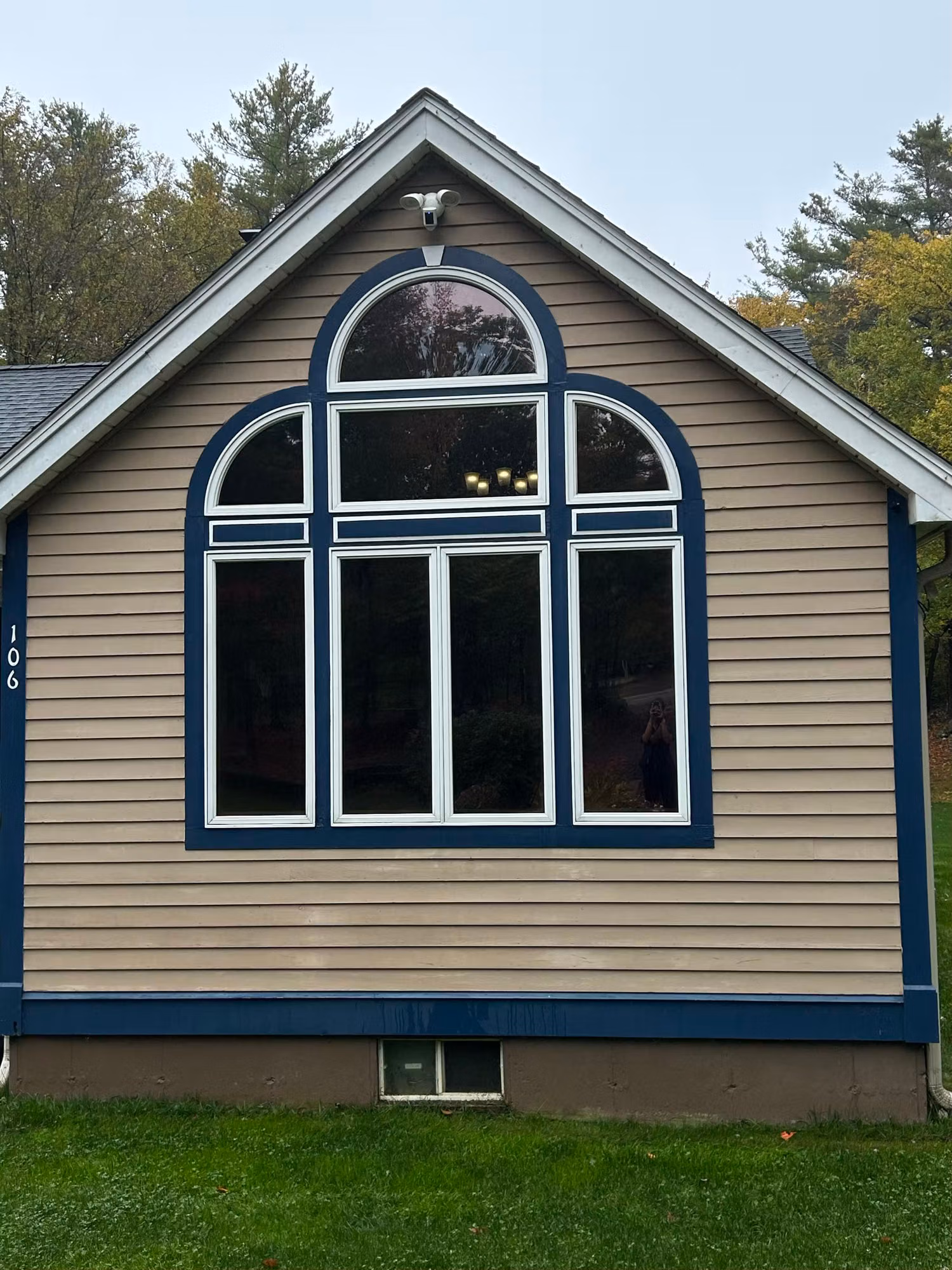 Exterior gable end of a home with a large arched Palladian window assembly and blue and white trim.