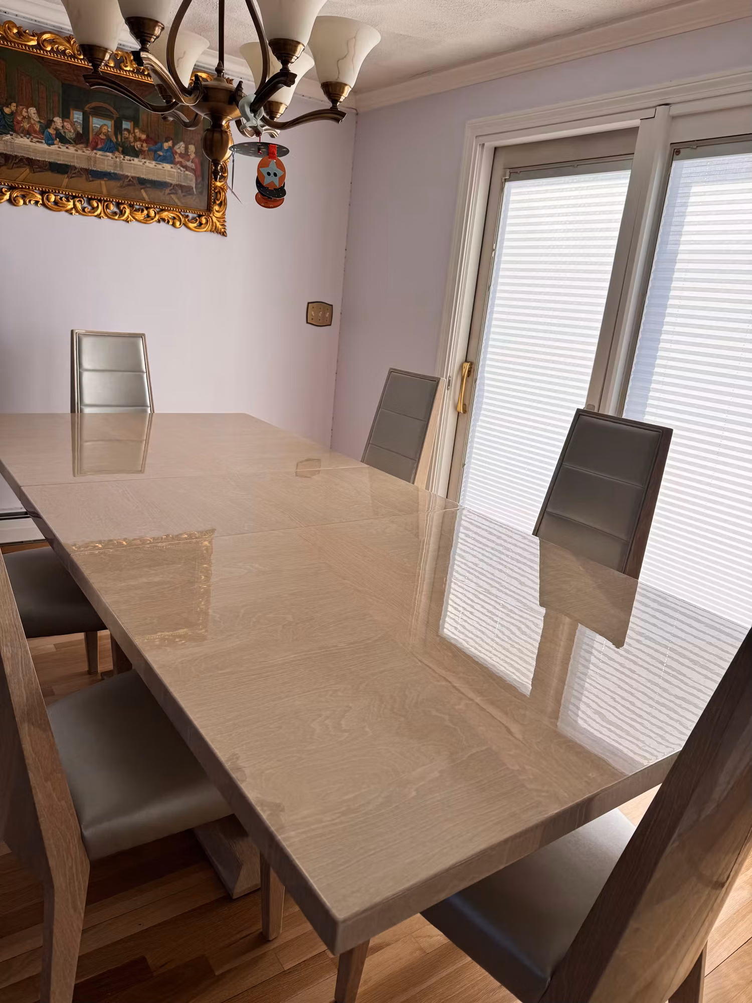 Dining room sliding glass door with a cellular shade beside a marble dining table and chairs.