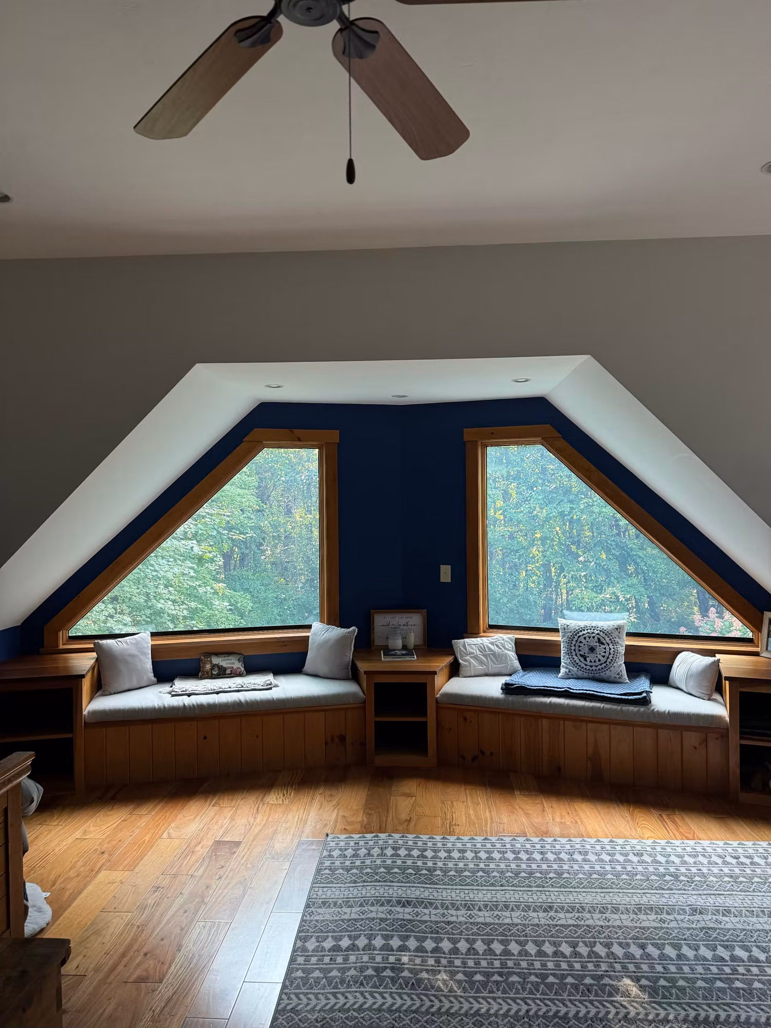 Bonus room with two angled dormer windows and built-in window seats overlooking trees.
