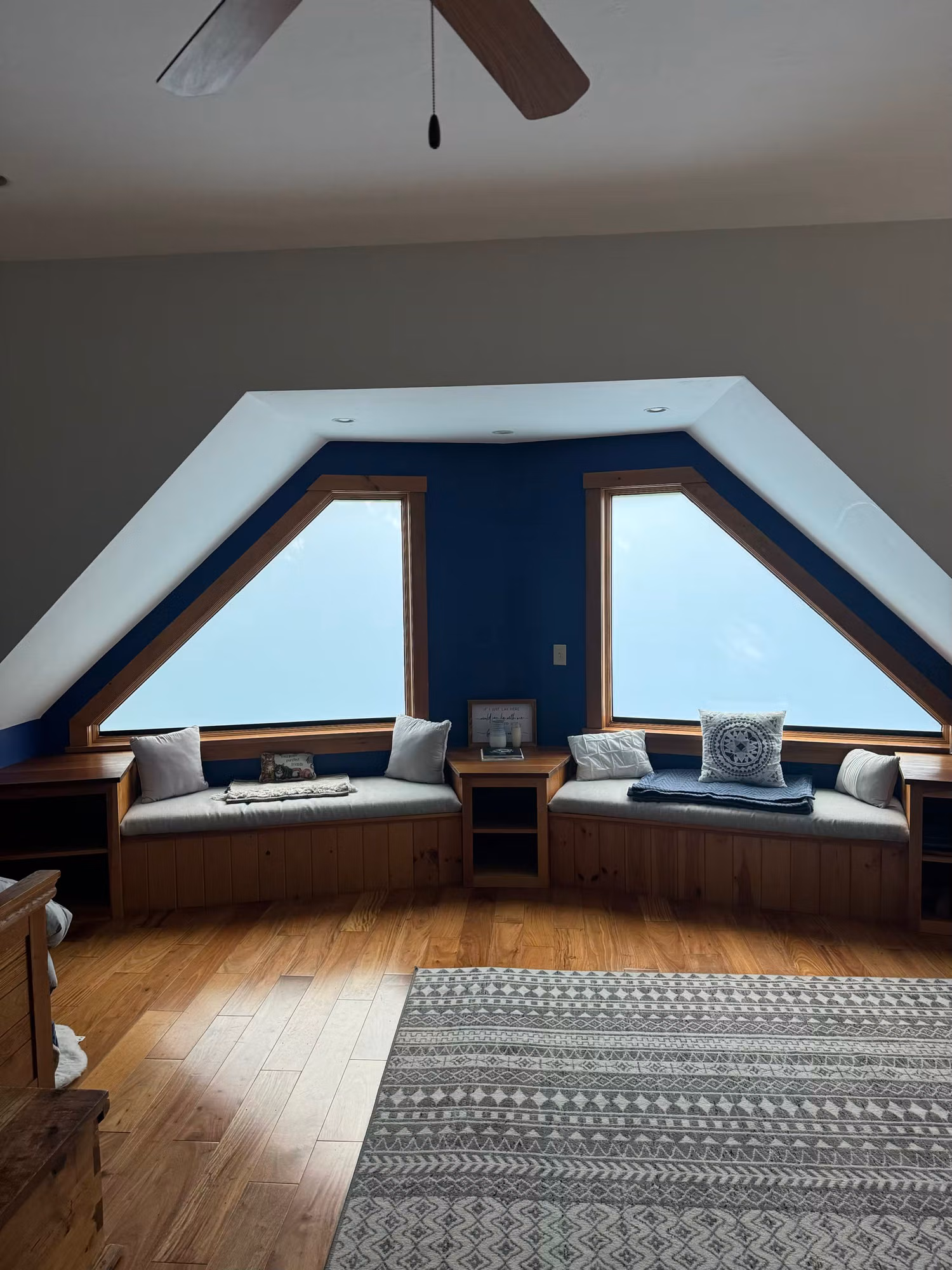 Angled dormer windows in a bonus room with built-in window seats and daylight from the trees outside.