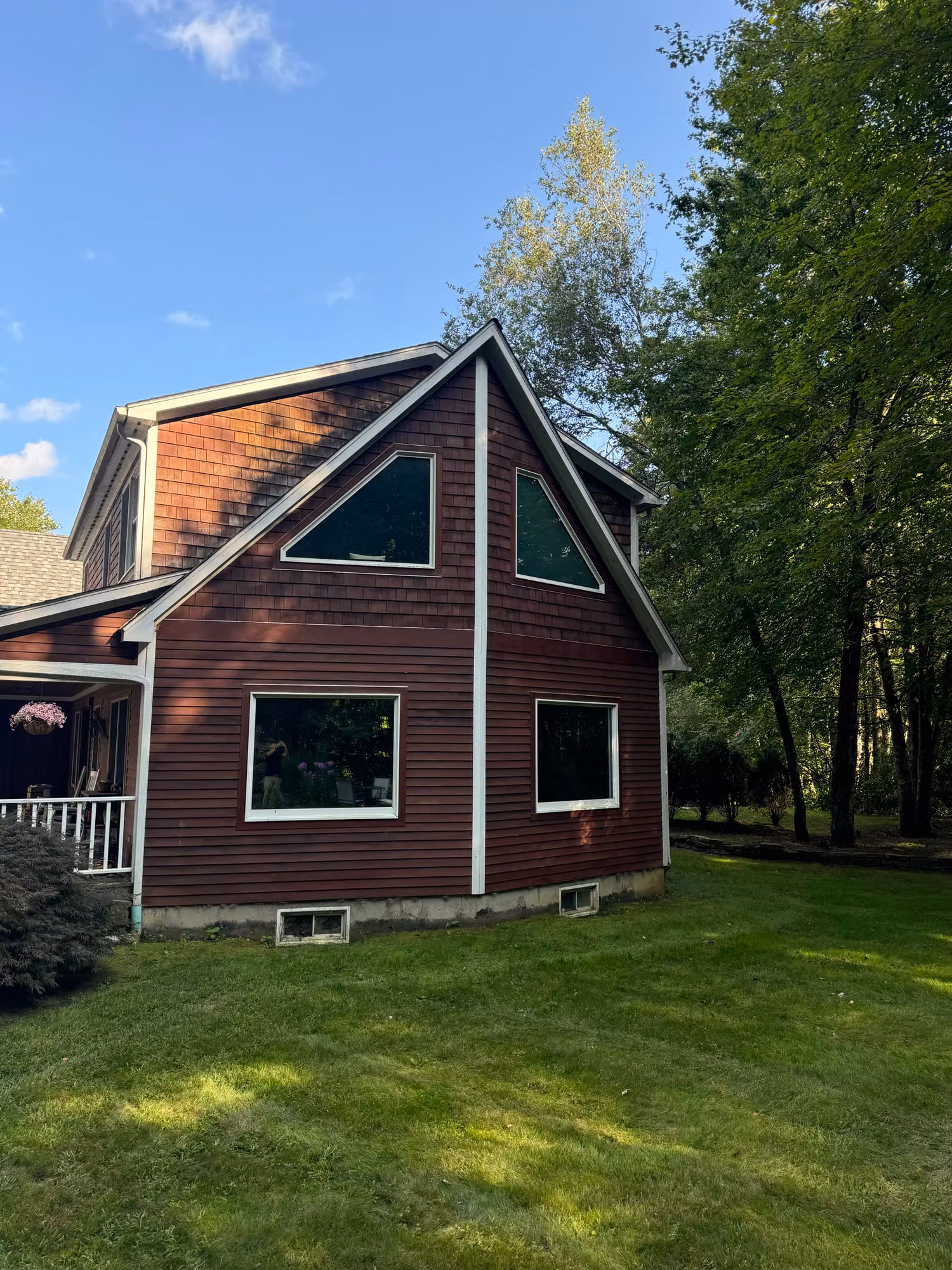 Exterior of a two-story red-sided home showing multiple windows including an upper gable window.