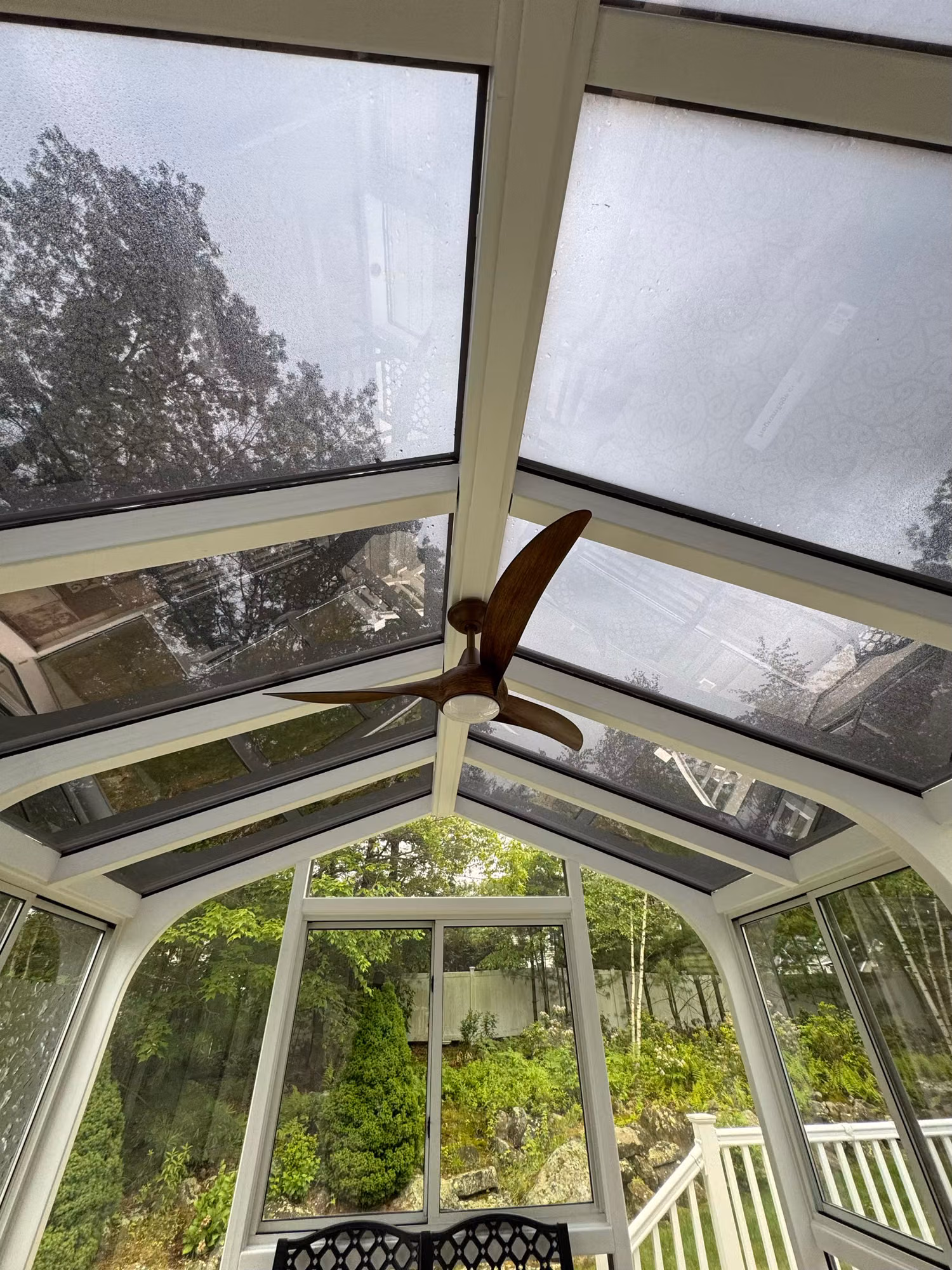 Light-diffusing solar control film on angled sunroom glass roof panels softening daylight over the seating area.