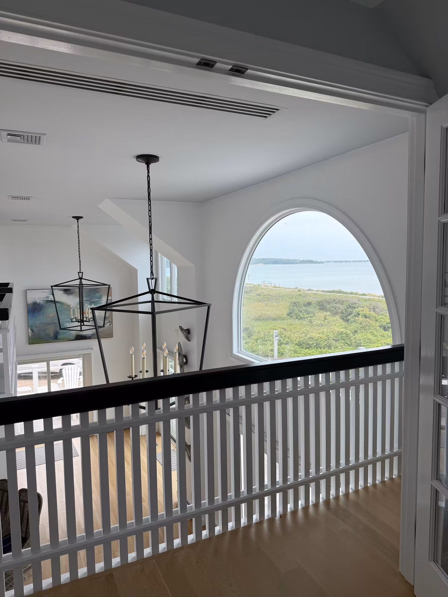 Arched picture window on an upstairs landing framing a bay view, treated with clear residential window film.