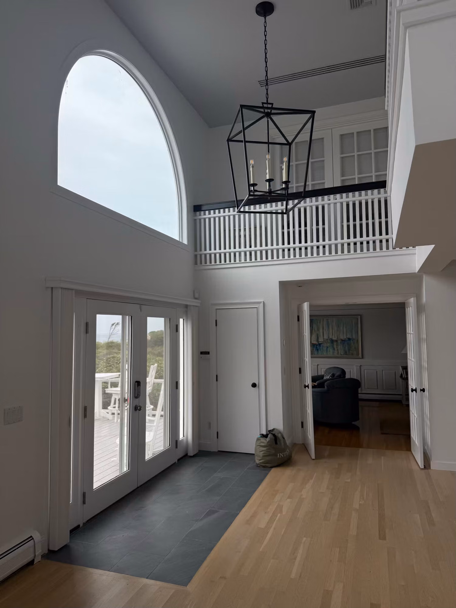 Two-story entry foyer with an arched window and French doors to a deck, glazing treated with clear film.