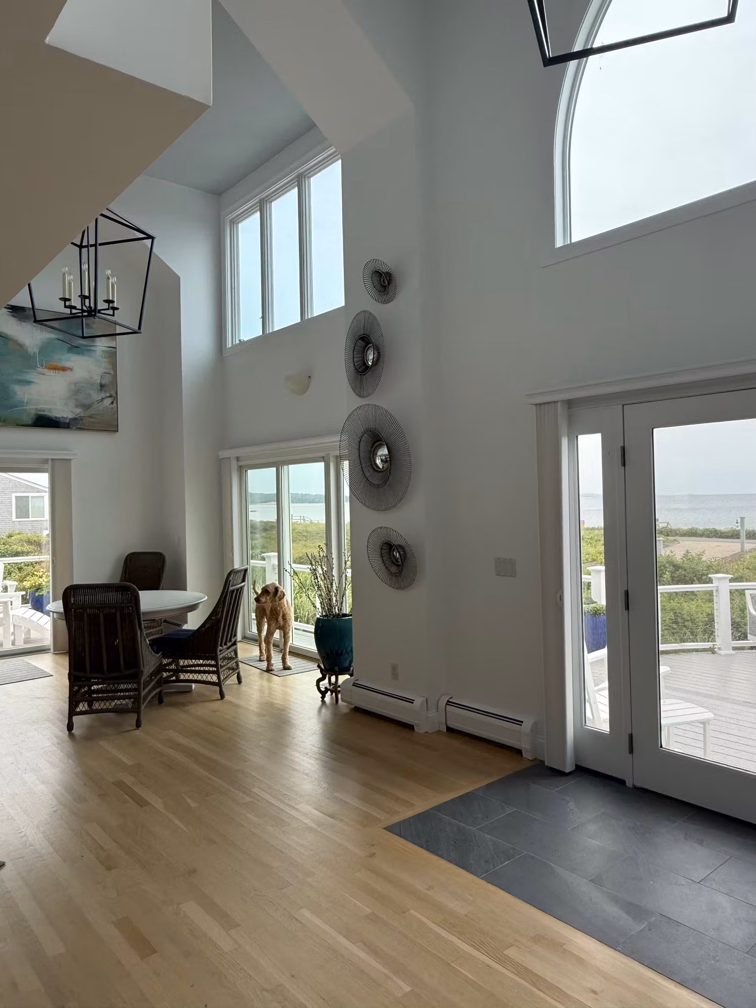Tall great room window wall and glass door with clear film overlooking the ocean and deck.