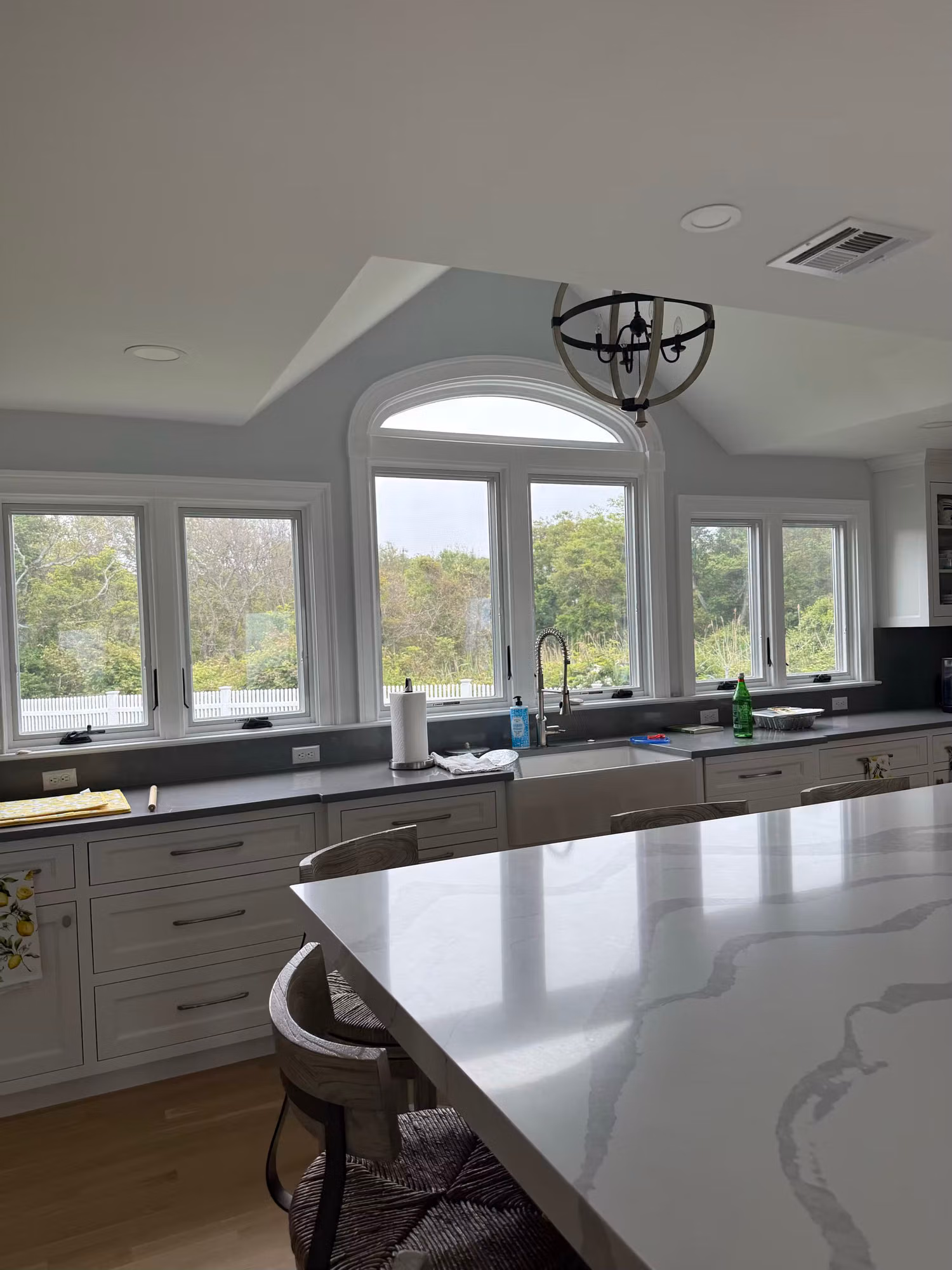 Bank of kitchen picture windows with an arched transom over the sink, filmed for a sunny coastal view.
