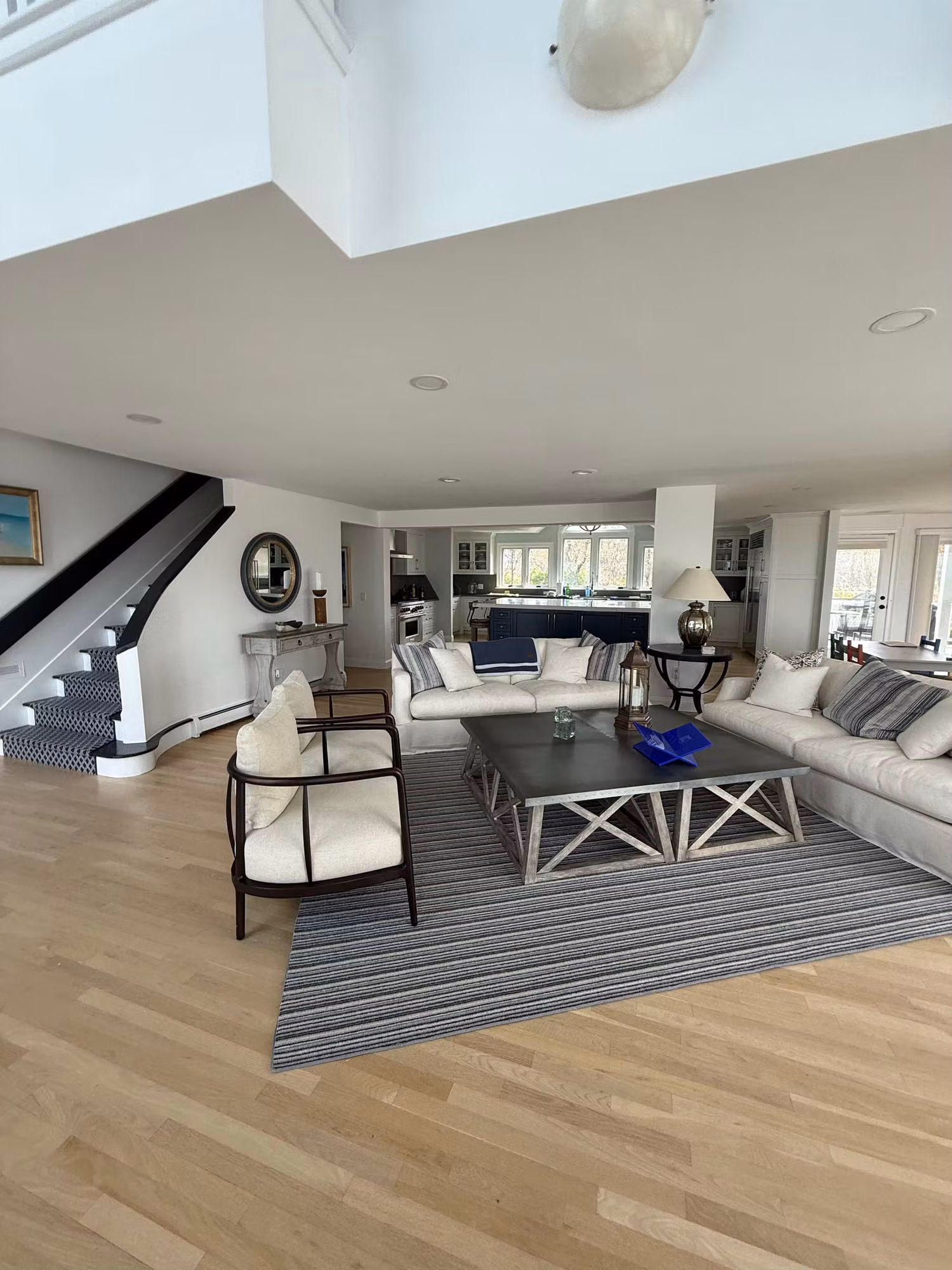 Open living room with a staircase and large rear windows treated with clear residential window film.