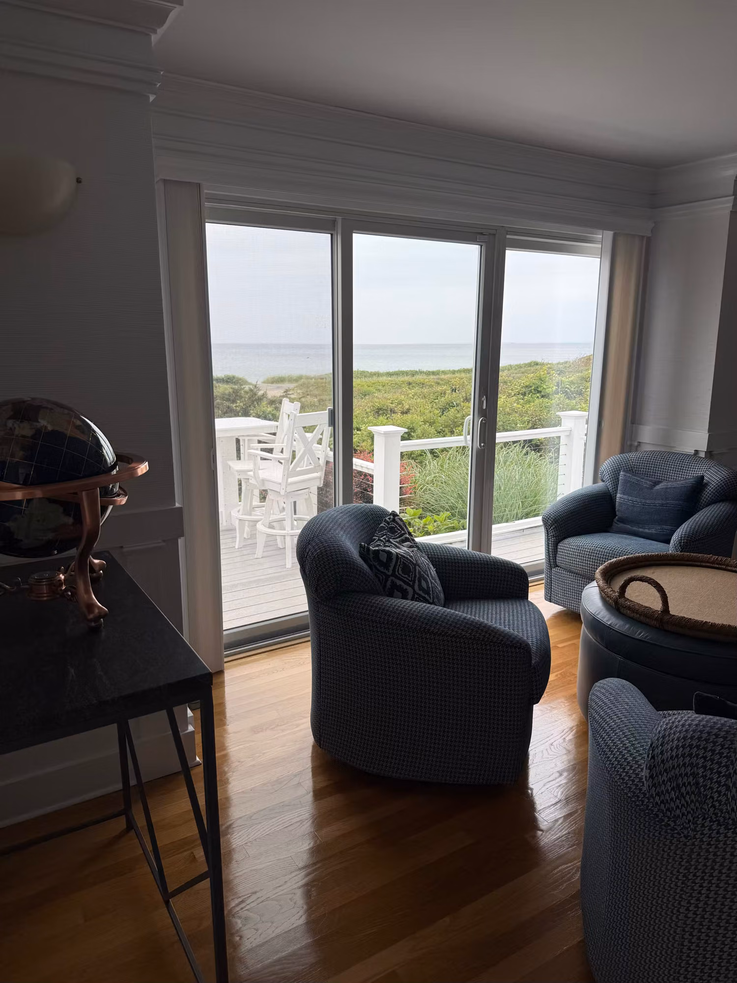 Living room sliding glass doors opening to an ocean-view deck with clear film on the glass.